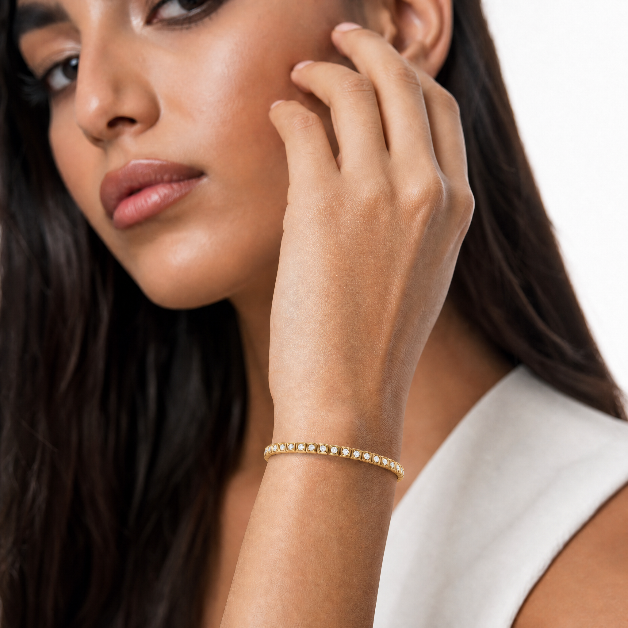 Elegant female model wearing a geometric lab grown diamond tennis bracelet in yellow gold by Raul Diamonds featuring modern luxury fine jewelry craftsmanship and timeless brilliance