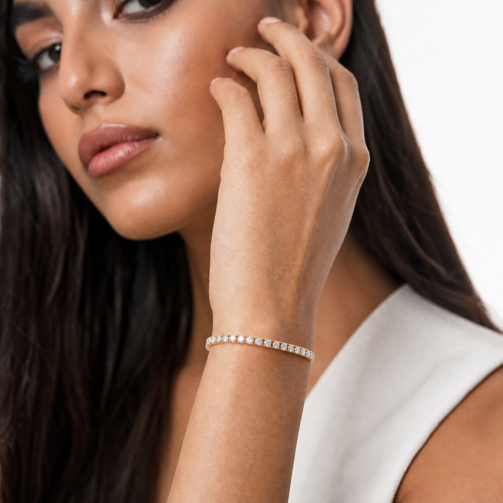 Luxury model wearing a 4 carat lab grown diamond tennis bracelet in yellow gold by Raul Diamonds with elegant wrist pose, soft luxury lighting, and premium fine jewelry styling