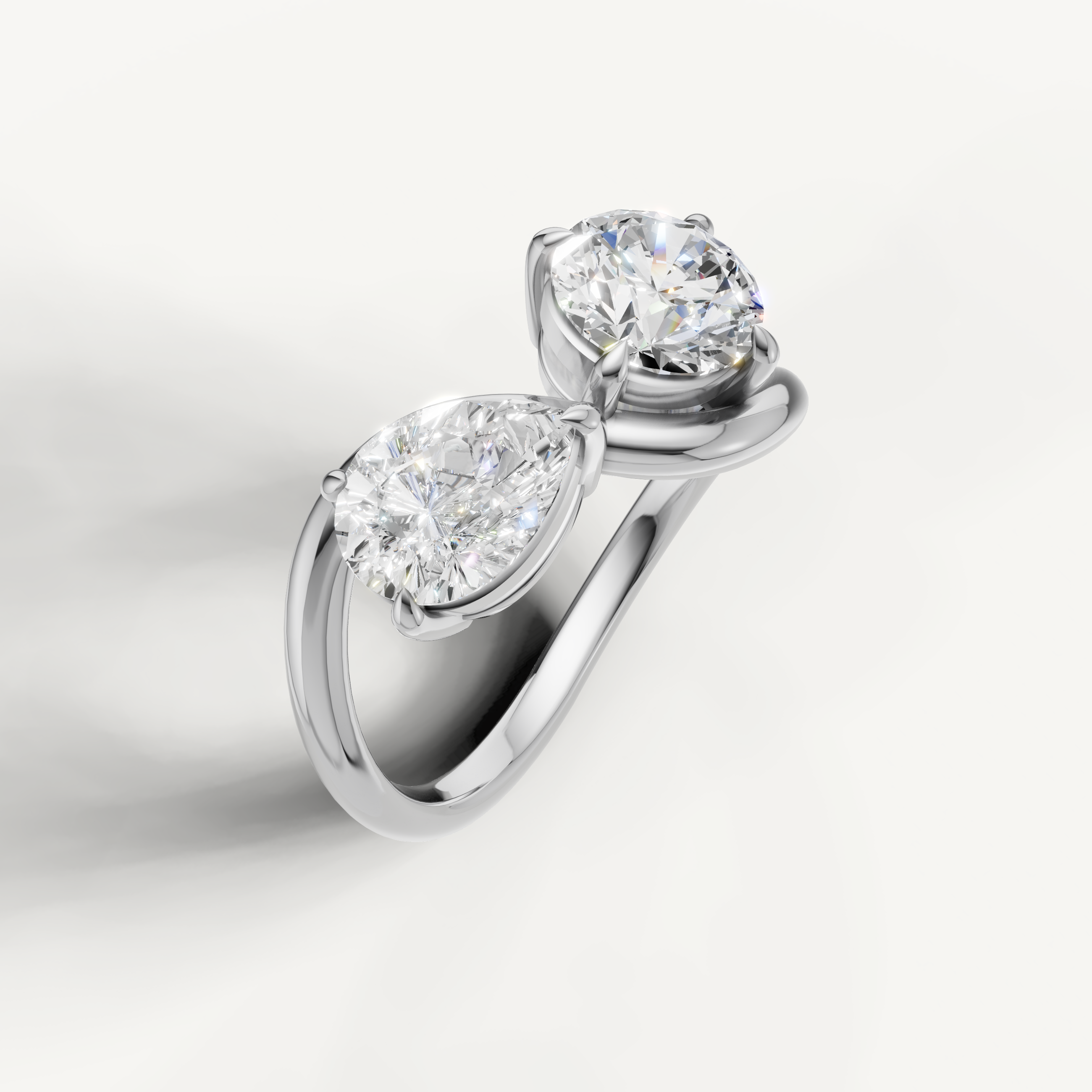 White gold two stone diamond ring featuring pear and round brilliant solitaire diamonds
