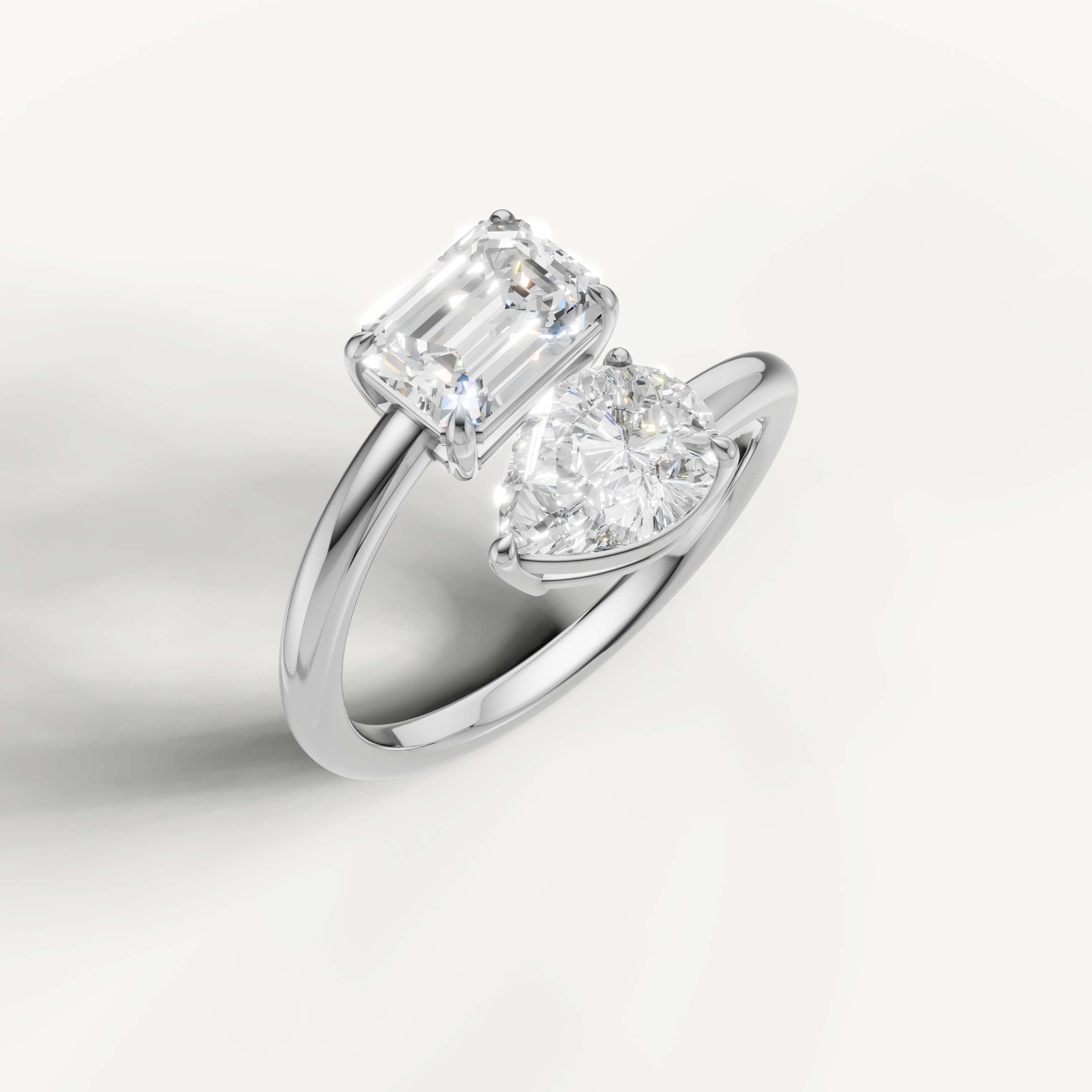 Elegant white gold open bypass ring with emerald cut and pear shaped diamonds
