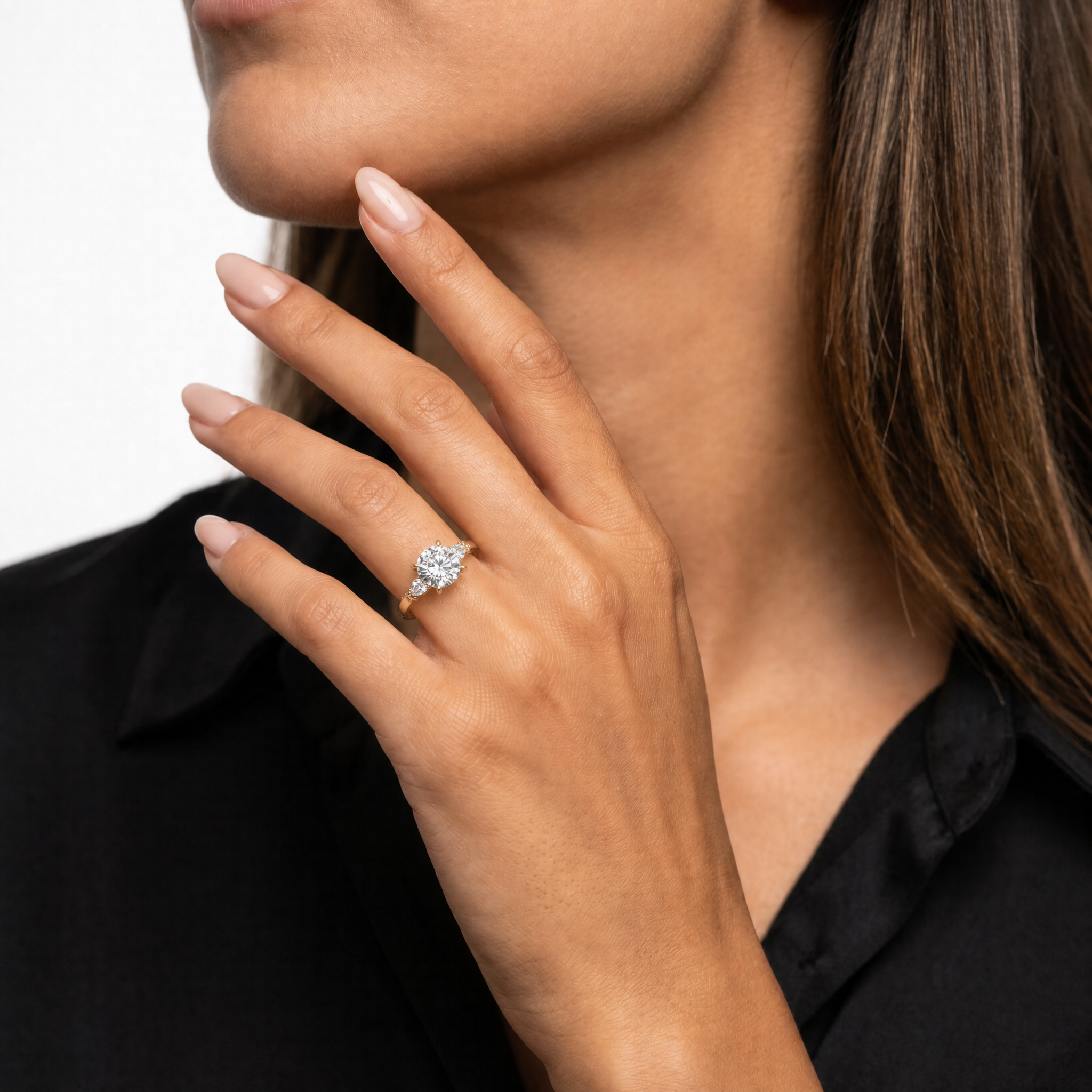 Elegant model wearing the Raul Diamonds Celeste round brilliant diamond ring in 14k white gold, featuring a classic center stone and sophisticated pear-shaped side diamonds