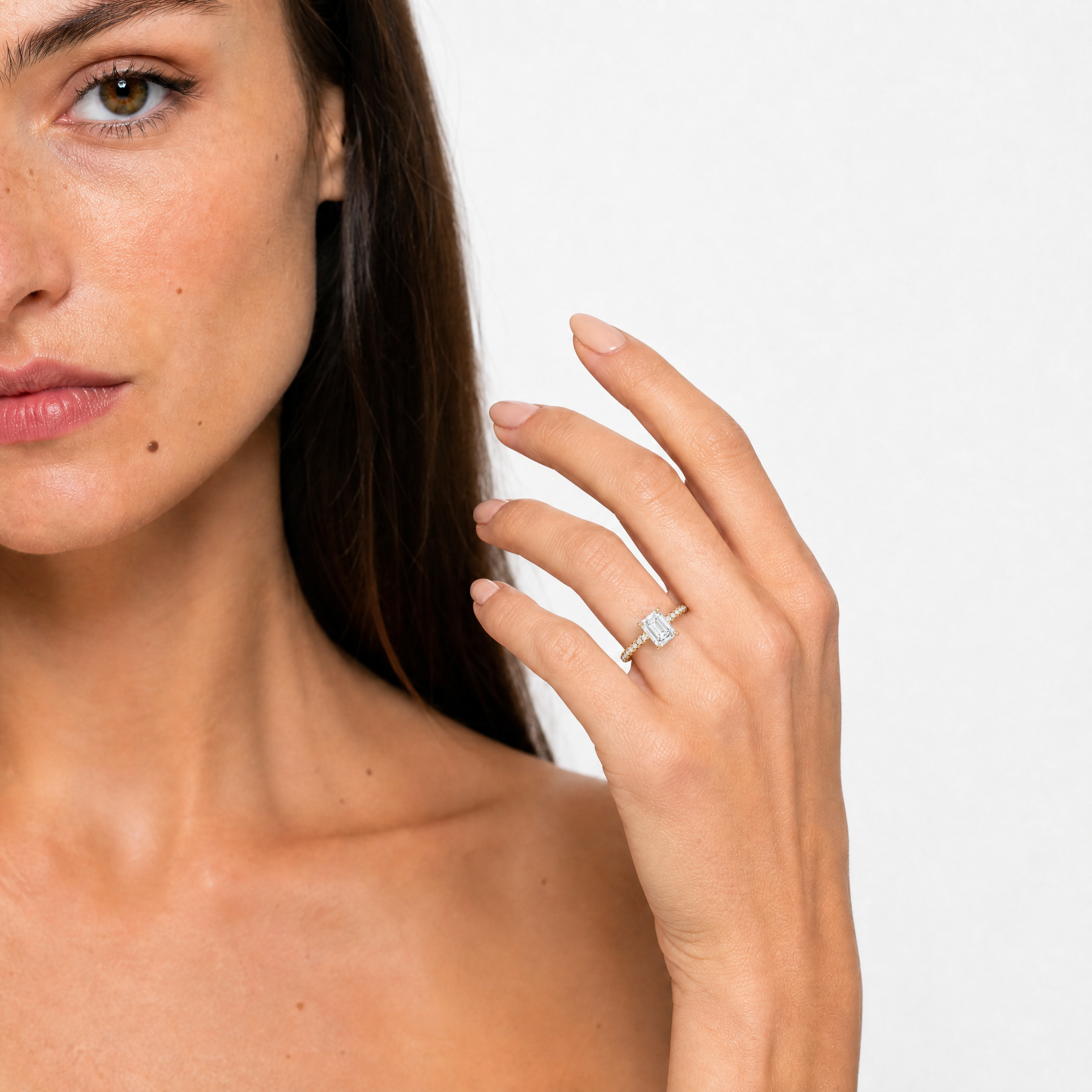 Elegant model wearing a Raul Diamonds emerald cut diamond engagement ring with a pavé diamond band on her finger, showcasing the luxury and clarity of the step-cut stone