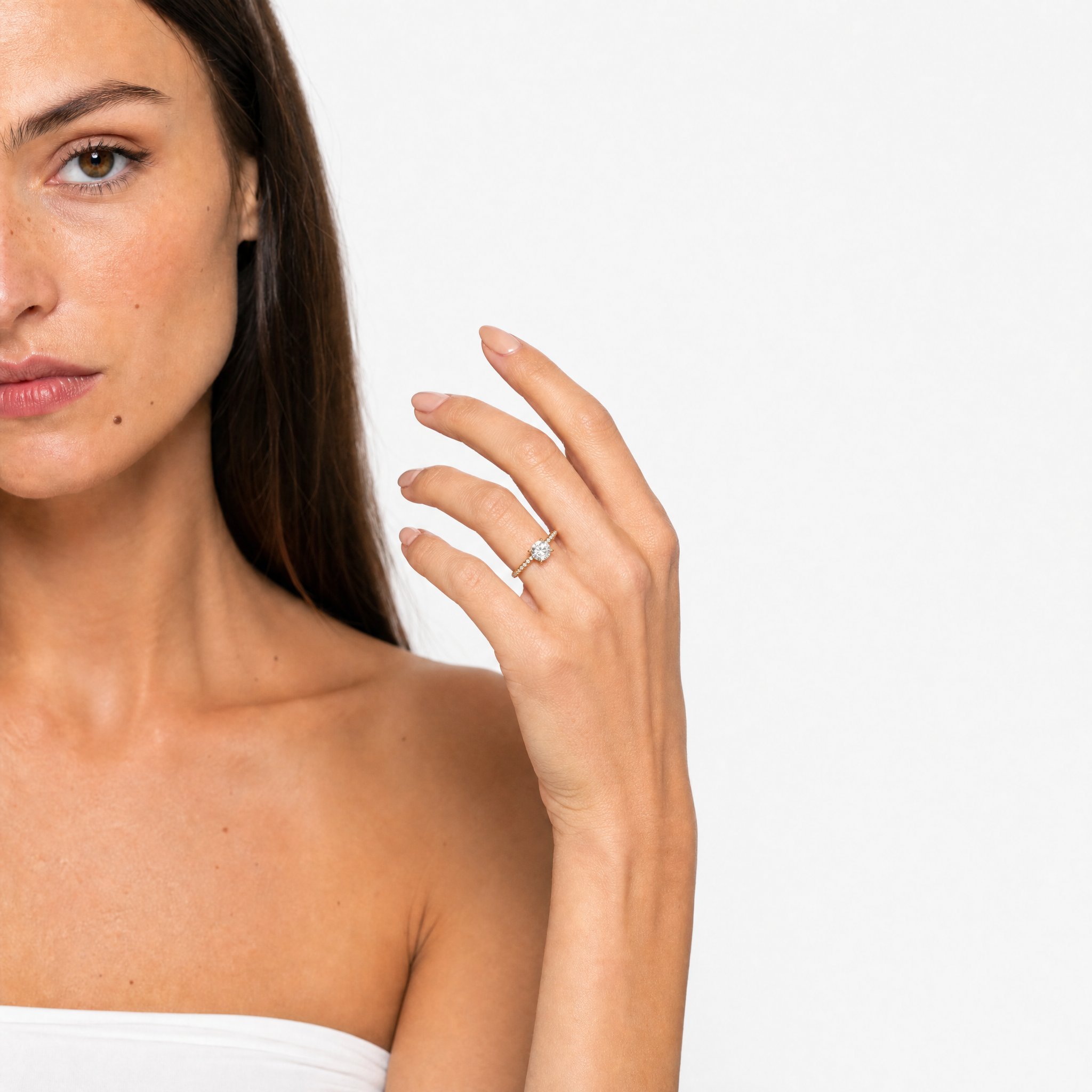 Elegant close-up of a hand model wearing a Raul Diamonds round brilliant cut engagement ring, showcasing the maximum light reflection of the diamond and the delicate pavé-set band.