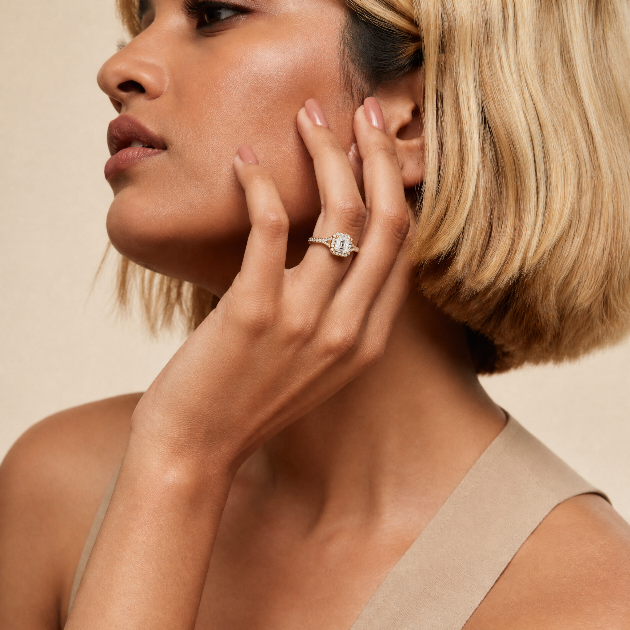 A close-up of a model's hand wearing a Raul Diamonds Asscher cut diamond engagement ring with a sparkling halo and diamond-set split shank band