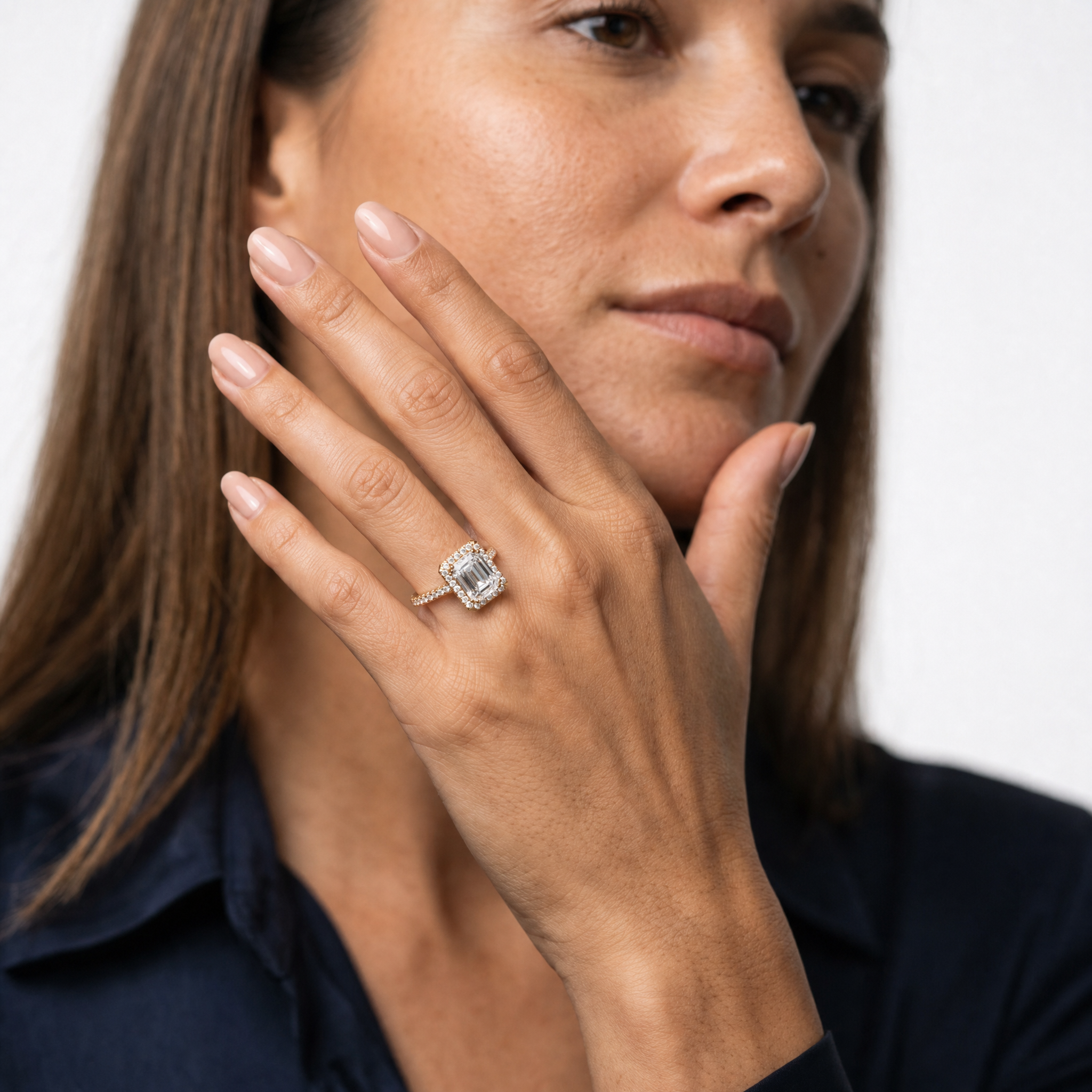 Model wearing an emerald cut lab grown diamond halo engagement ring in 14K gold by Raul Diamonds