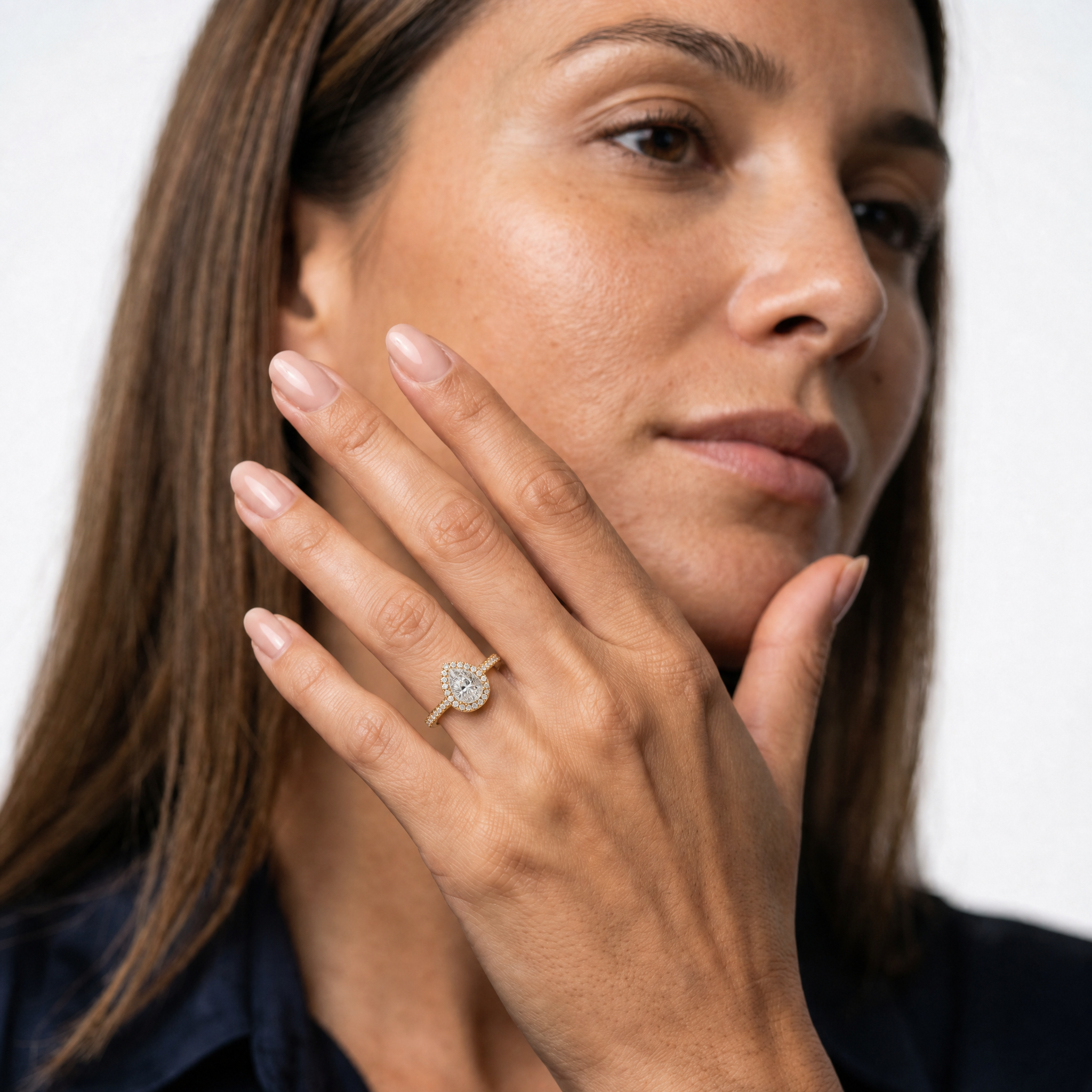 Model wearing a pear cut lab grown diamond halo engagement ring in 14K gold by Raul Diamonds