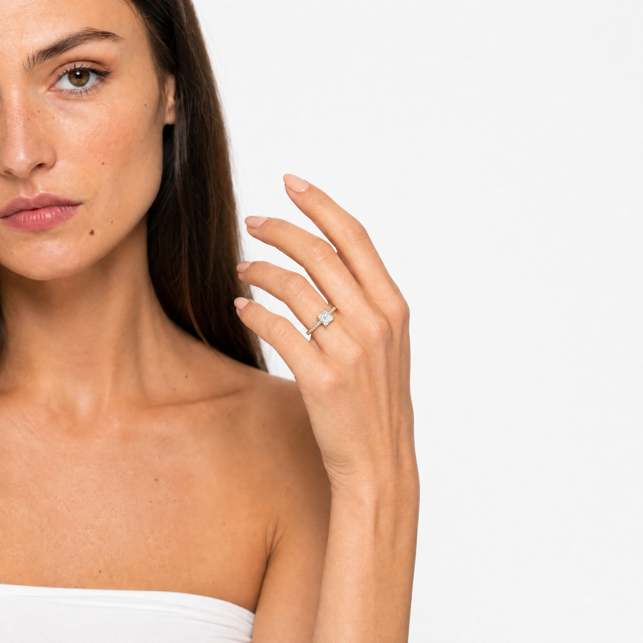 Elegant hand model showcasing a Raul Diamonds princess-cut engagement ring with a brilliant pavé-set band and hidden halo, highlighting the sharp architectural lines and luxury sparkle of the diamond.