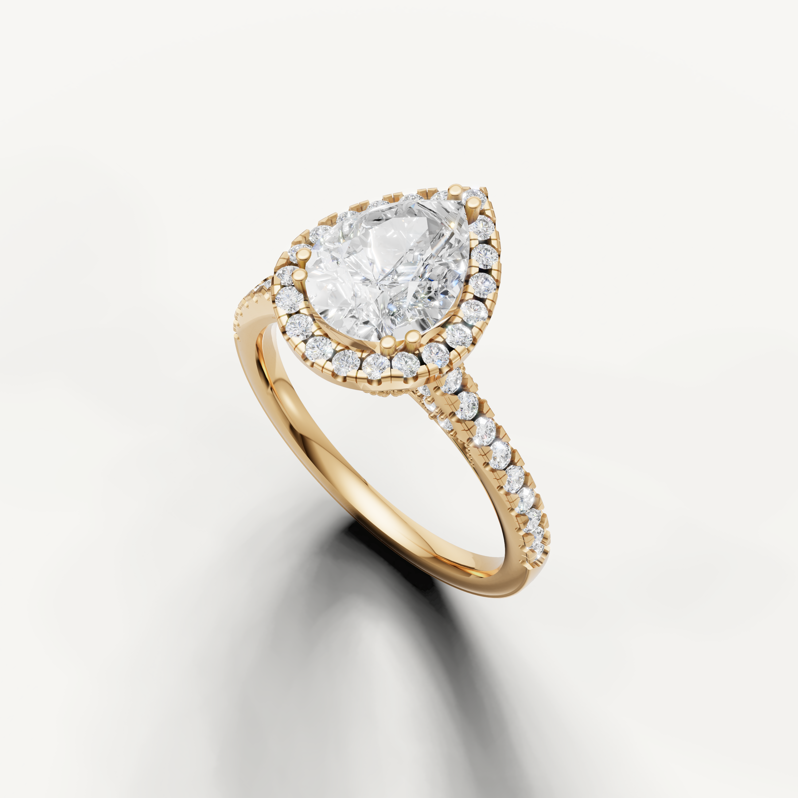 Yellow gold pear cut lab grown diamond ring featuring a classic halo setting and delicate pavé band