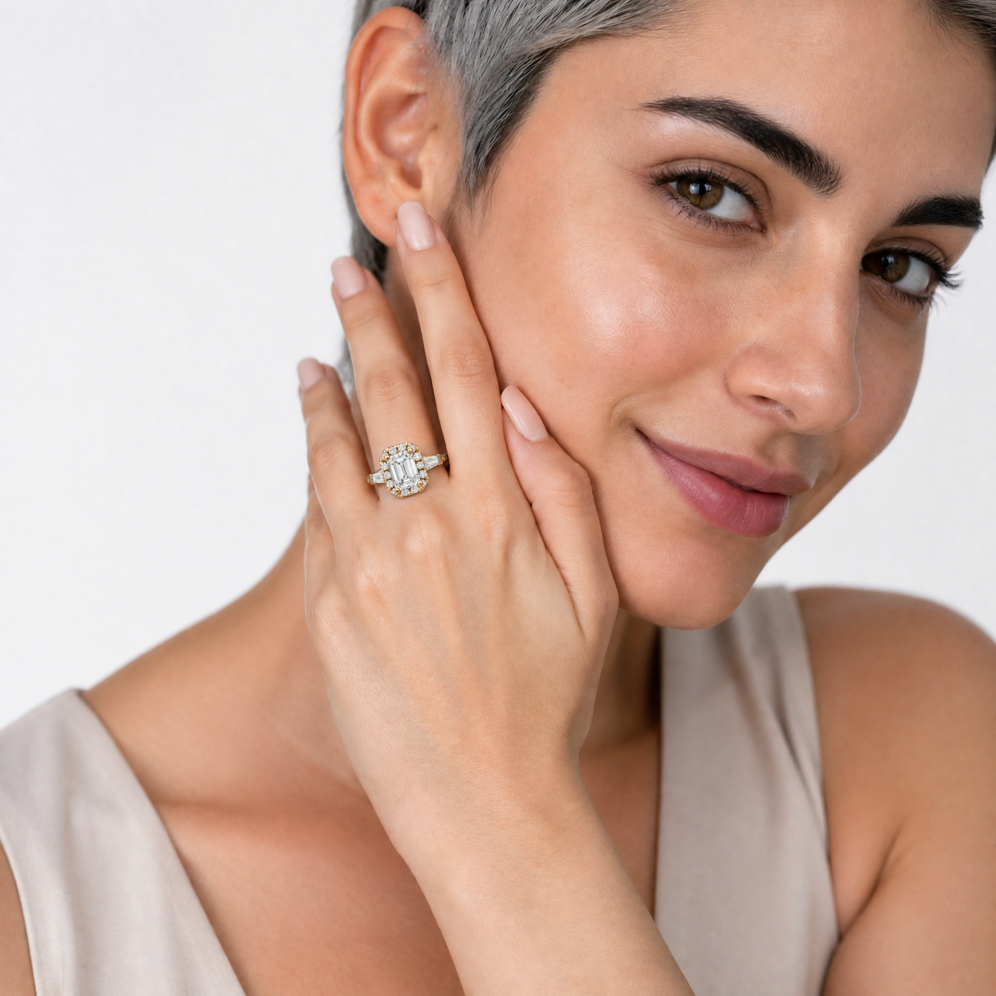 Model wearing Raul Diamonds emerald cut halo diamond engagement ring in yellow gold with tapered side stones