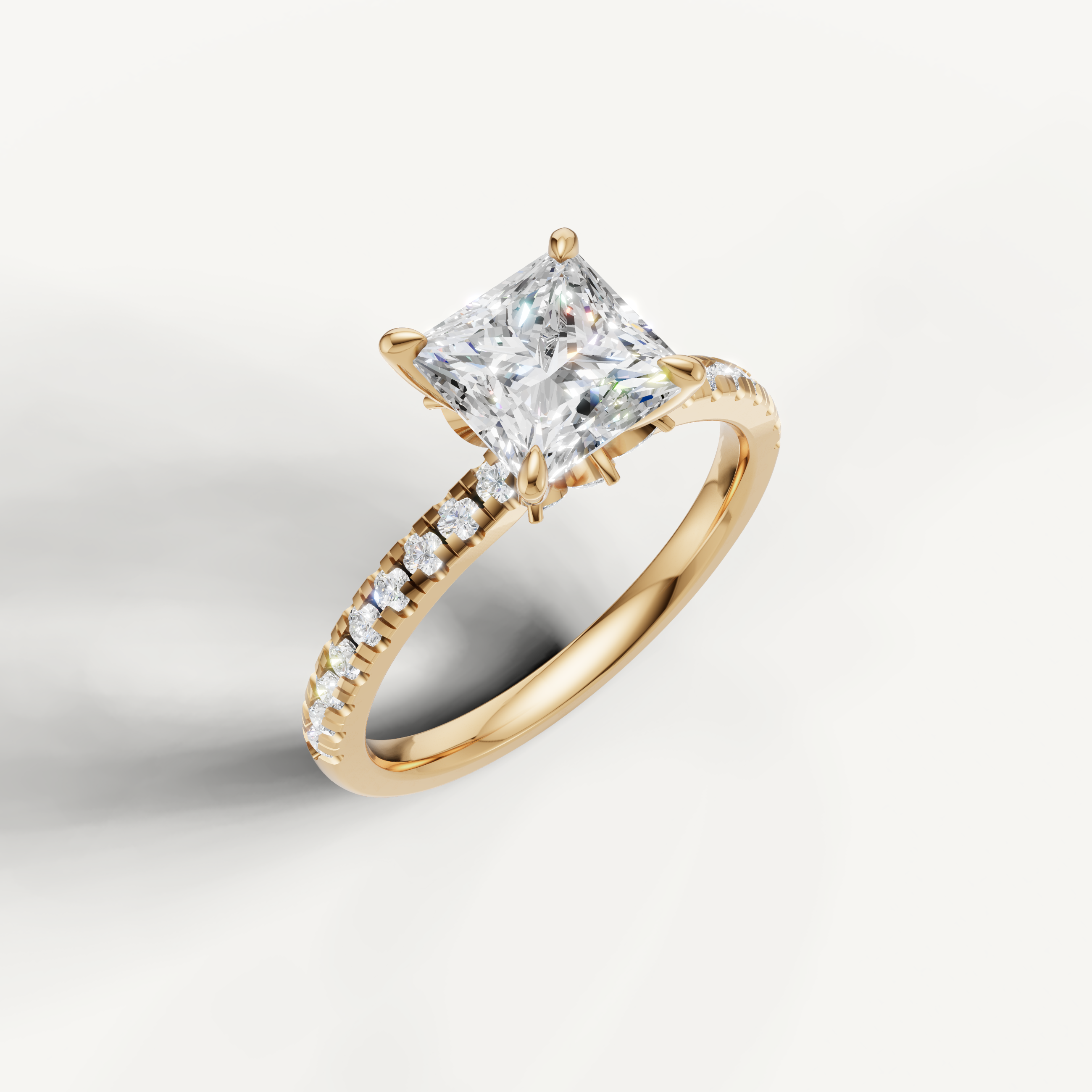 Yellow gold princess cut diamond ring with a delicate pavé diamond setting and a hidden halo for added brilliance.