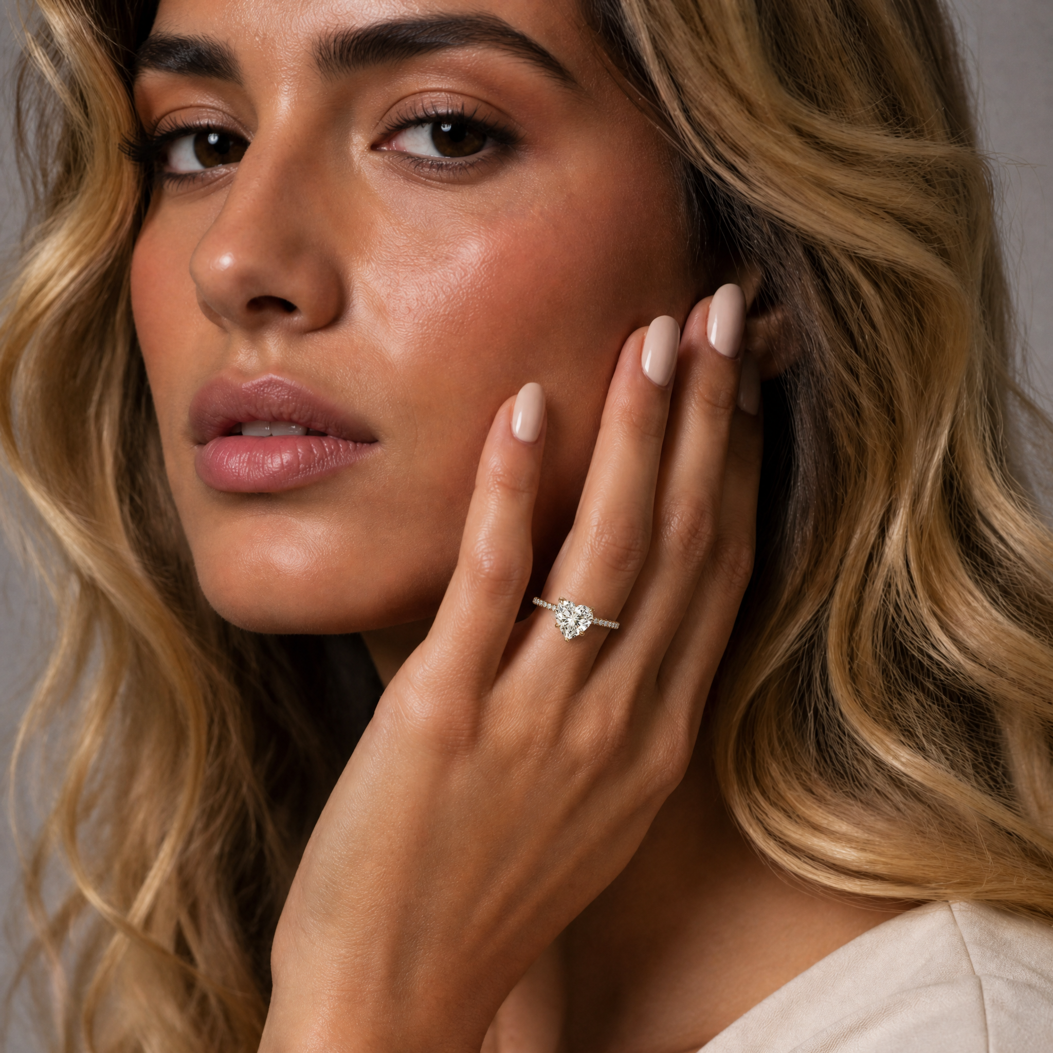 Model wearing Raul Diamonds heart cut lab grown diamond engagement ring in 14K yellow gold with pavé band and romantic solitaire design