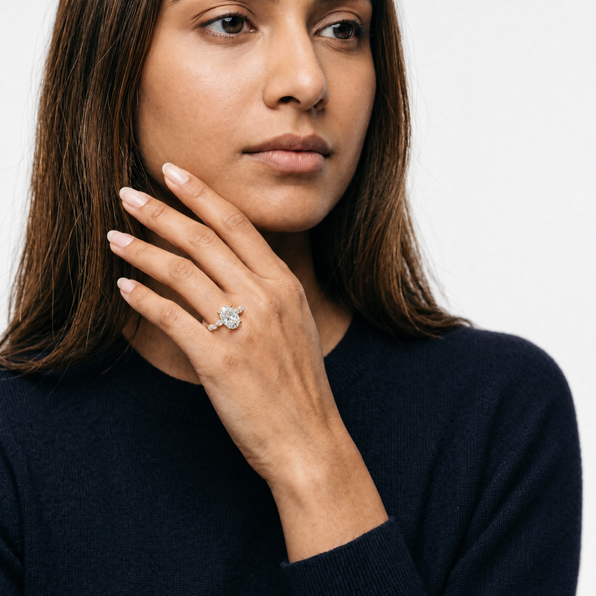 Model wearing oval cut lab grown diamond engagement ring in 14K gold with marquise side stones by Raul Diamonds