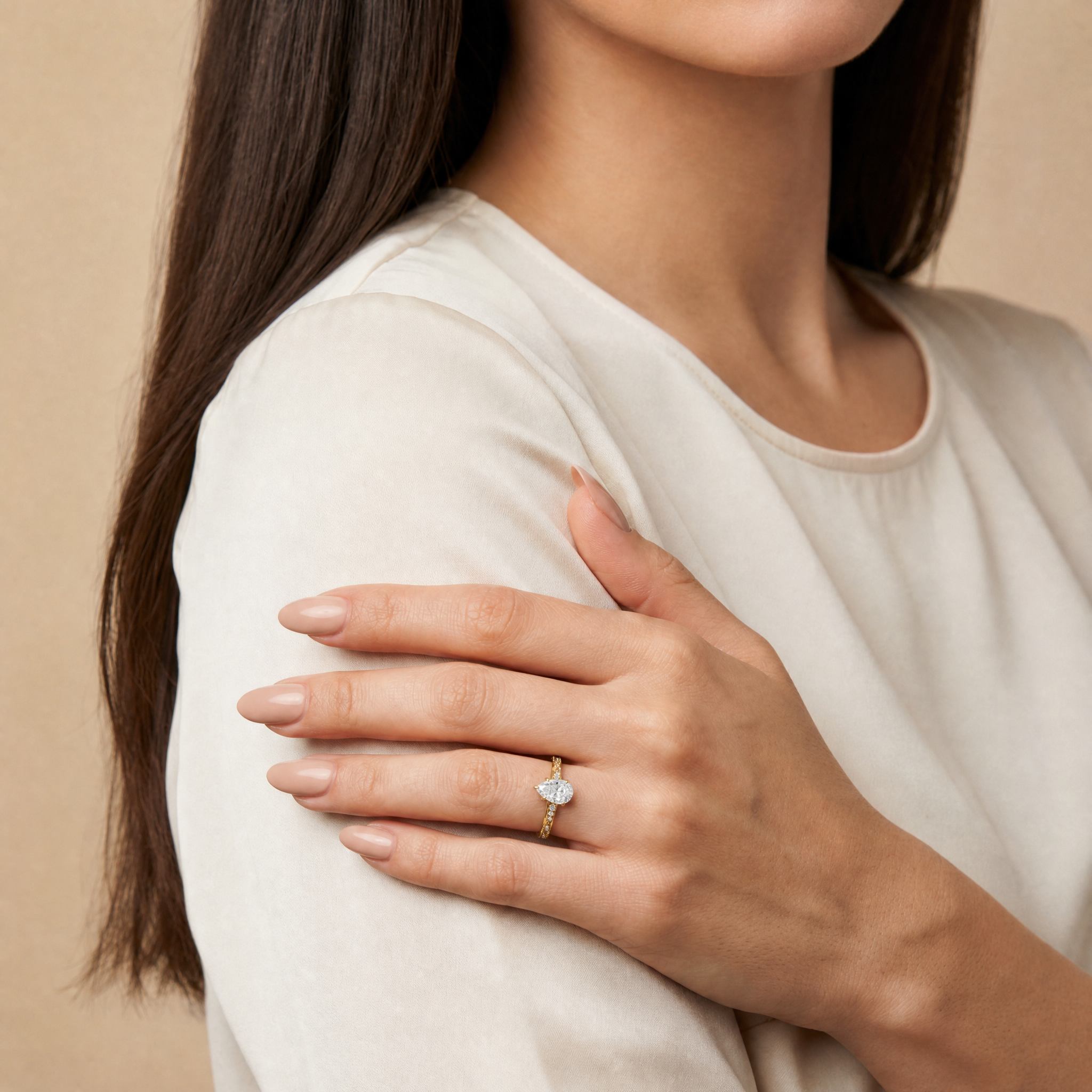 Model wearing Raul Diamonds pear cut lab grown diamond engagement ring in 14K gold with elegant twisted pavé band