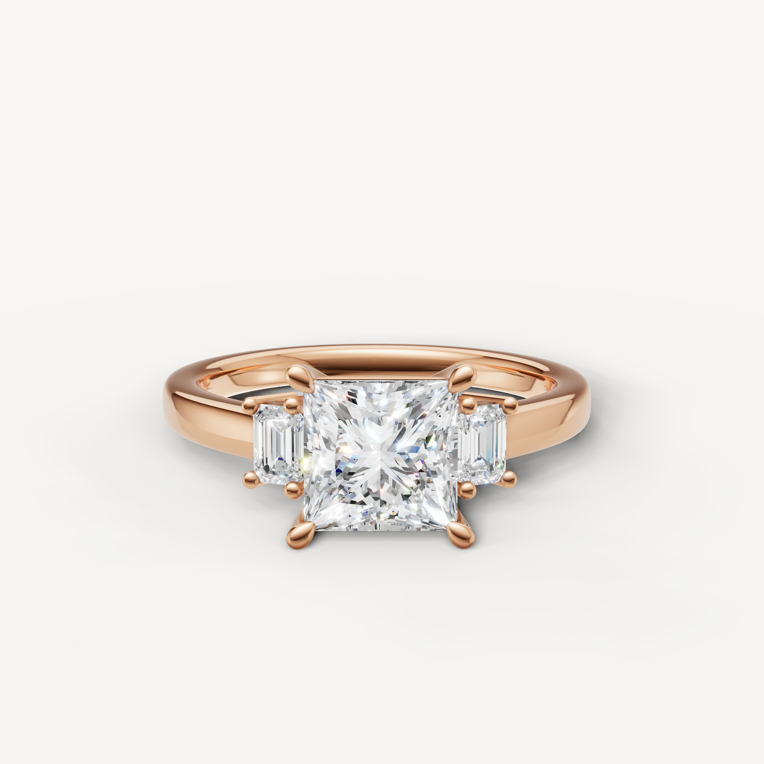 Princess cut lab grown diamond three stone engagement ring in 14K rose gold with emerald cut side stones