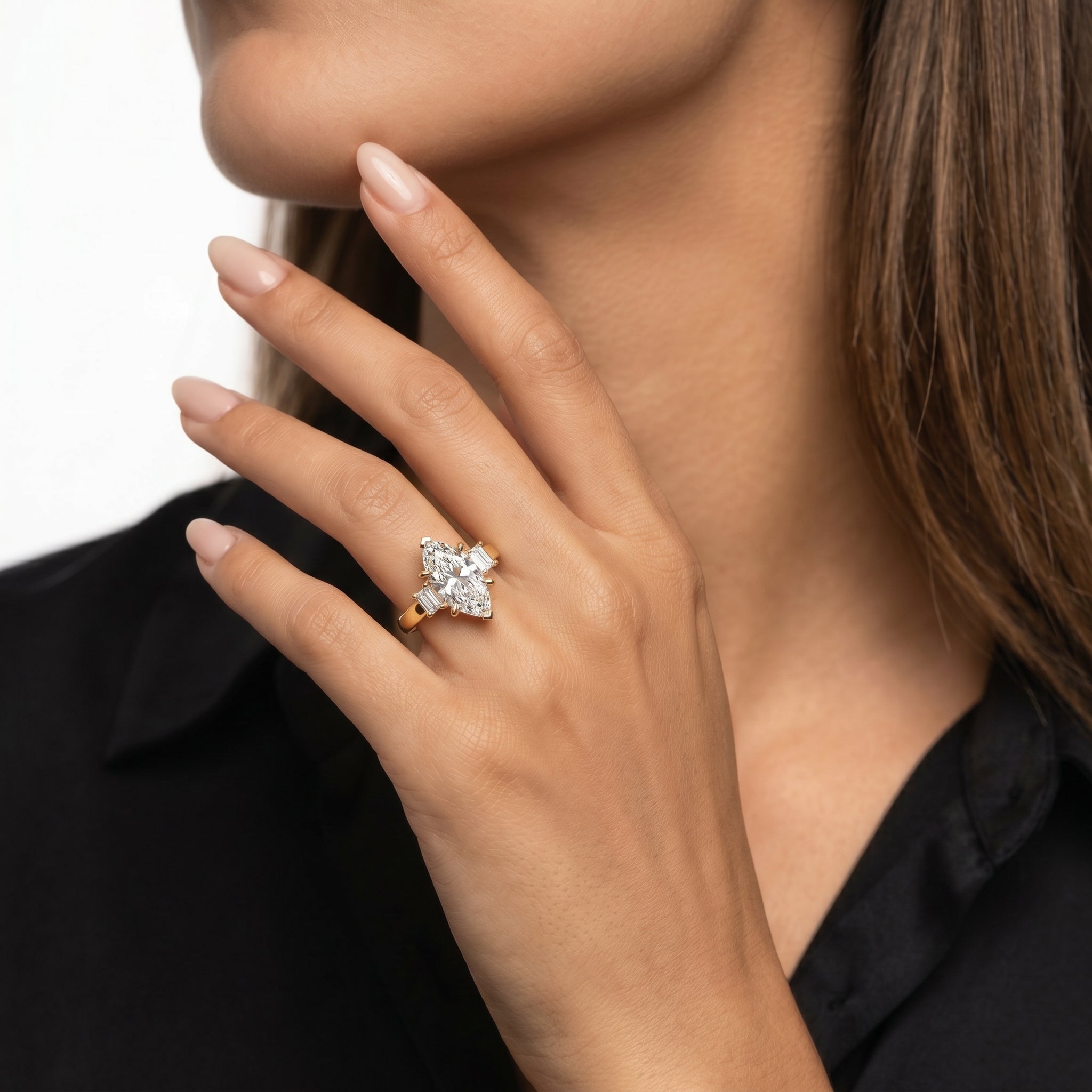 Close-up of a hand model wearing a Rual Diamonds marquise-cut three-stone engagement ring featuring trillion-cut side diamonds and a brilliant pavé-set diamond band