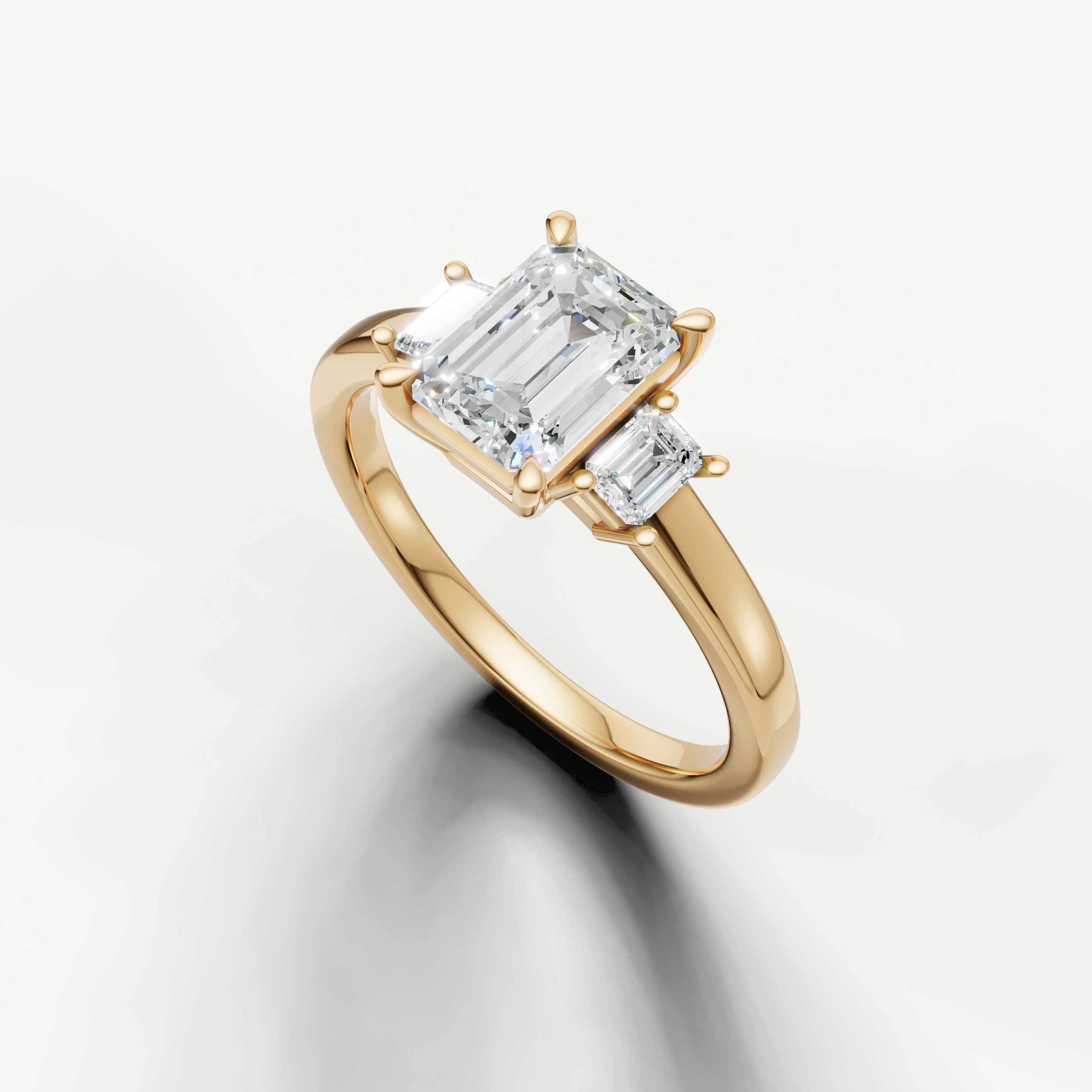 Modern emerald cut three stone lab grown diamond ring in yellow gold with minimalist band
