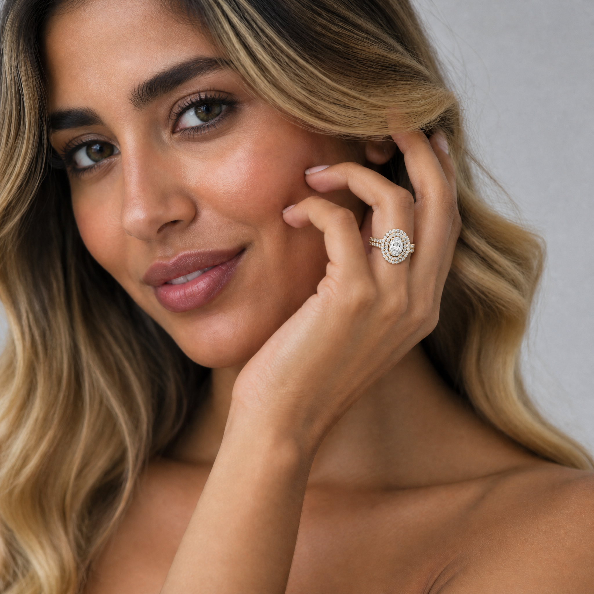 Model wearing Raul Diamonds oval halo diamond engagement ring in yellow gold with double halo pavé setting