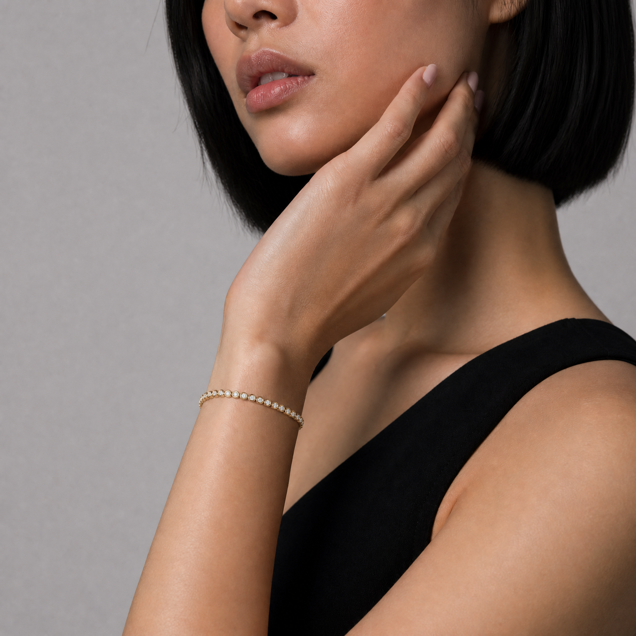 Elegant fashion model wearing a bezel set lab grown diamond tennis bracelet in yellow gold by Raul Diamonds featuring timeless luxury jewelry craftsmanship and modern elegance