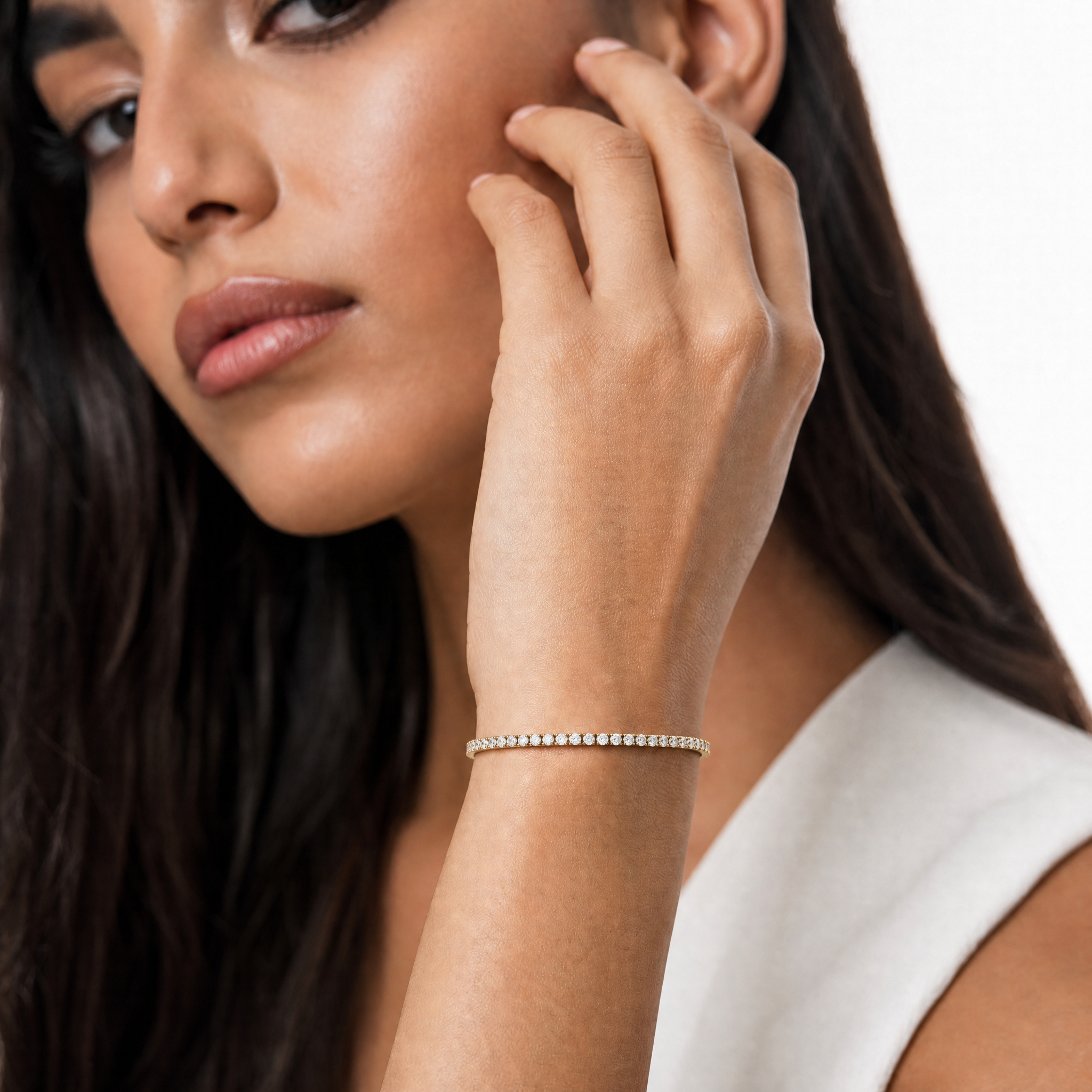 Luxury female model wearing a 2 carat lab grown diamond tennis bracelet in yellow gold by Raul Diamonds with elegant styling and soft luxury lighting