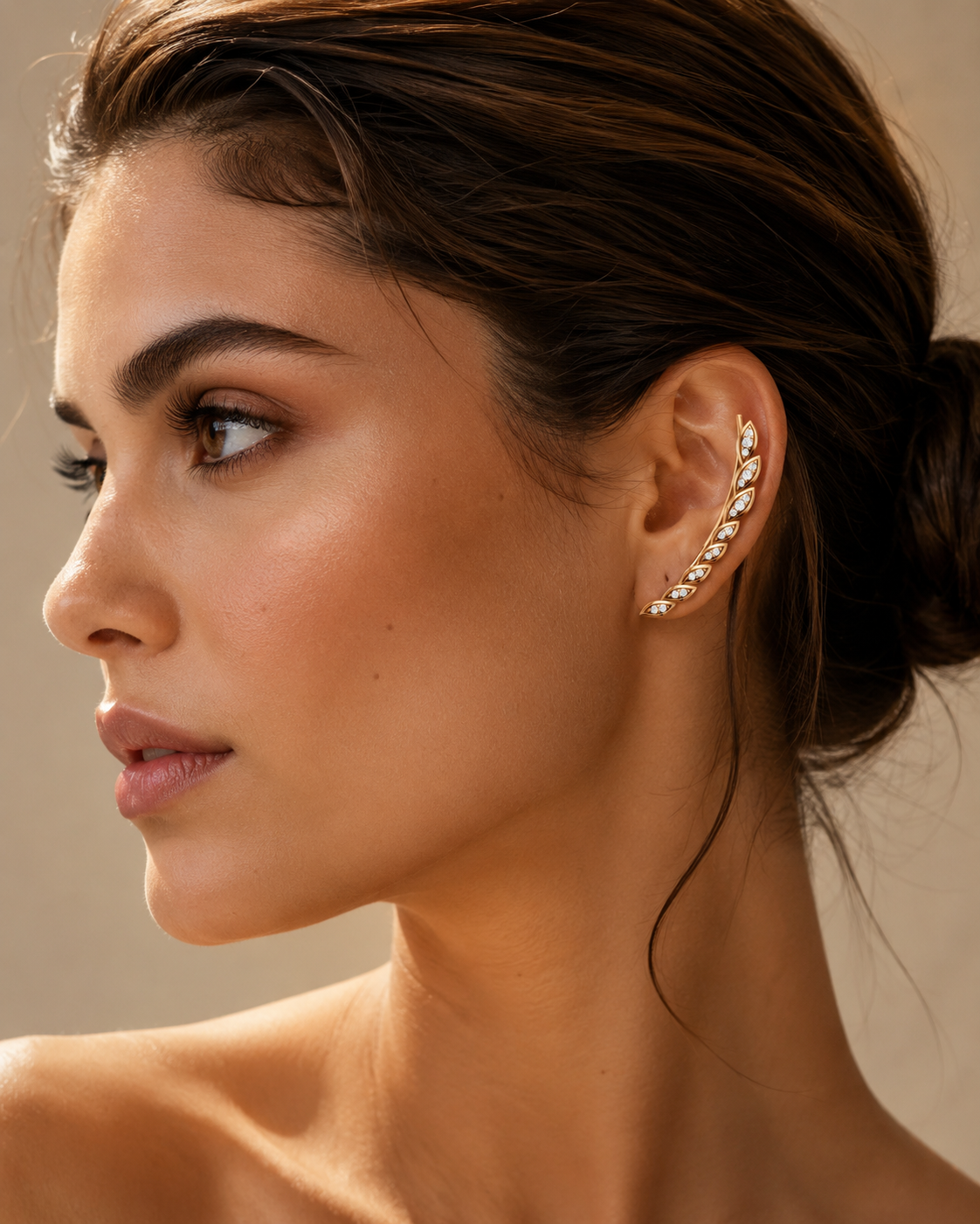 Woman wearing a yellow gold diamond ear climber earring with marquise-shaped diamonds in a luxury close-up portrait.