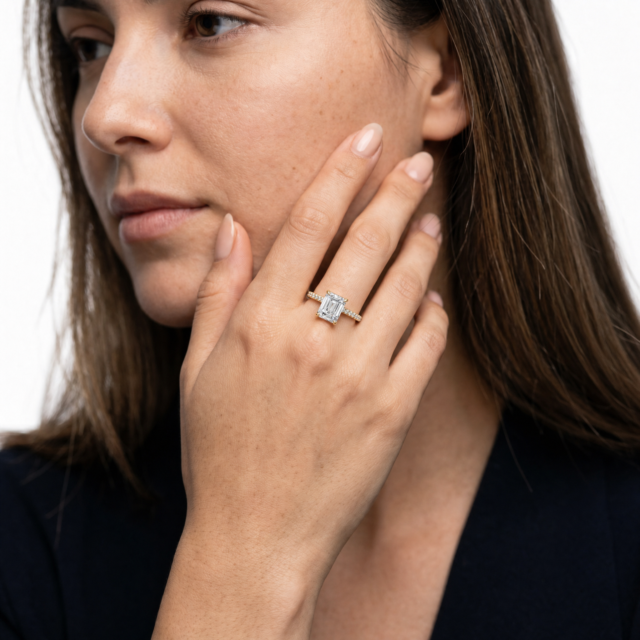Model wearing Raul Diamonds emerald cut lab grown diamond engagement ring in yellow gold with a shimmering pavé diamond band and refined luxury bridal style