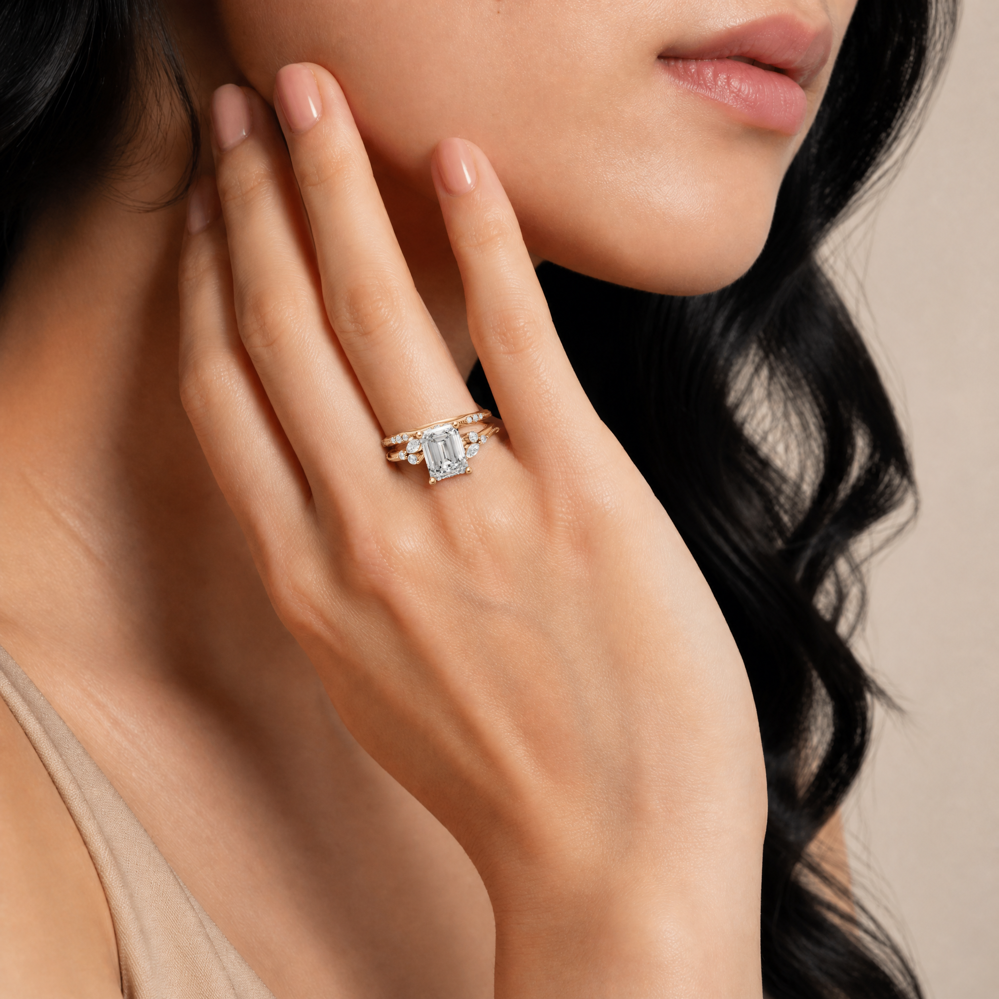 Model wearing Raul Diamonds yellow gold emerald cut lab grown diamond engagement ring with matching curved diamond wedding band and marquise accent details