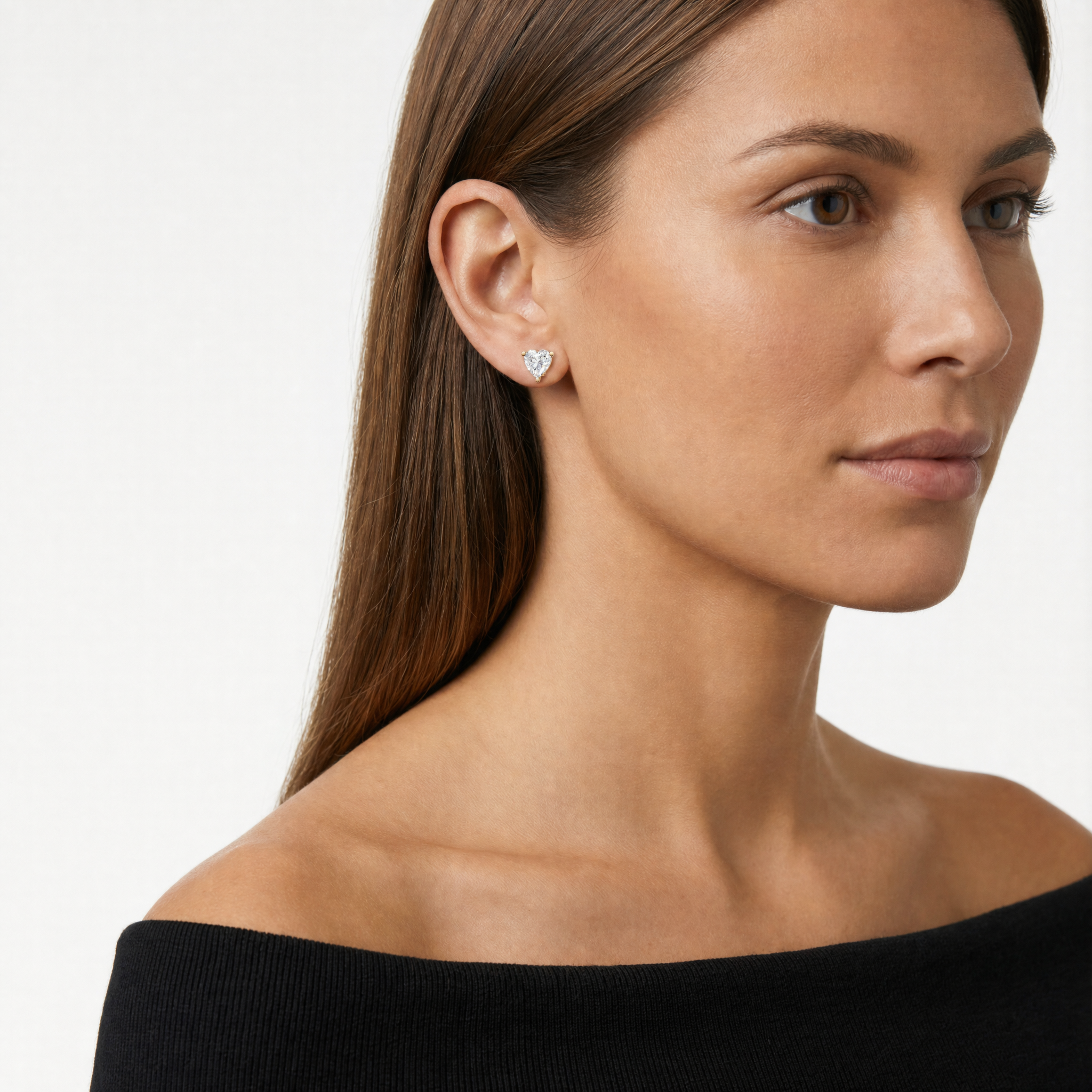 Model wearing Raul Diamonds yellow gold heart shaped lab grown diamond stud earrings with classic three prong solitaire setting and brilliant sparkle