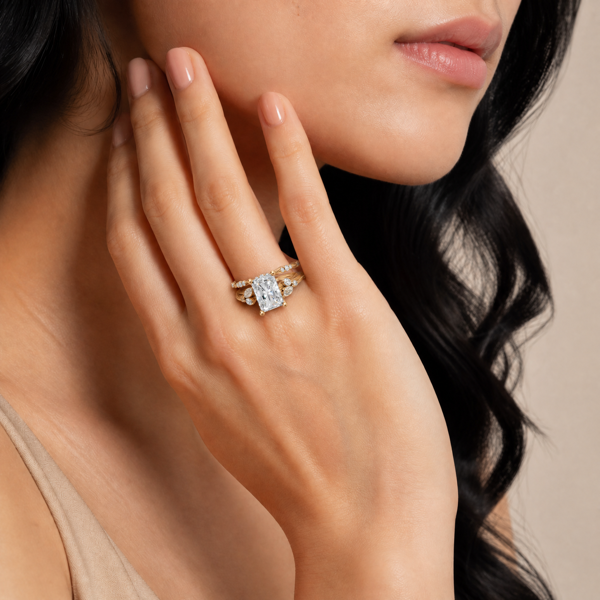 Model wearing Raul Diamonds yellow gold radiant cut lab grown diamond engagement ring with curved diamond wedding bands and marquise side stone details