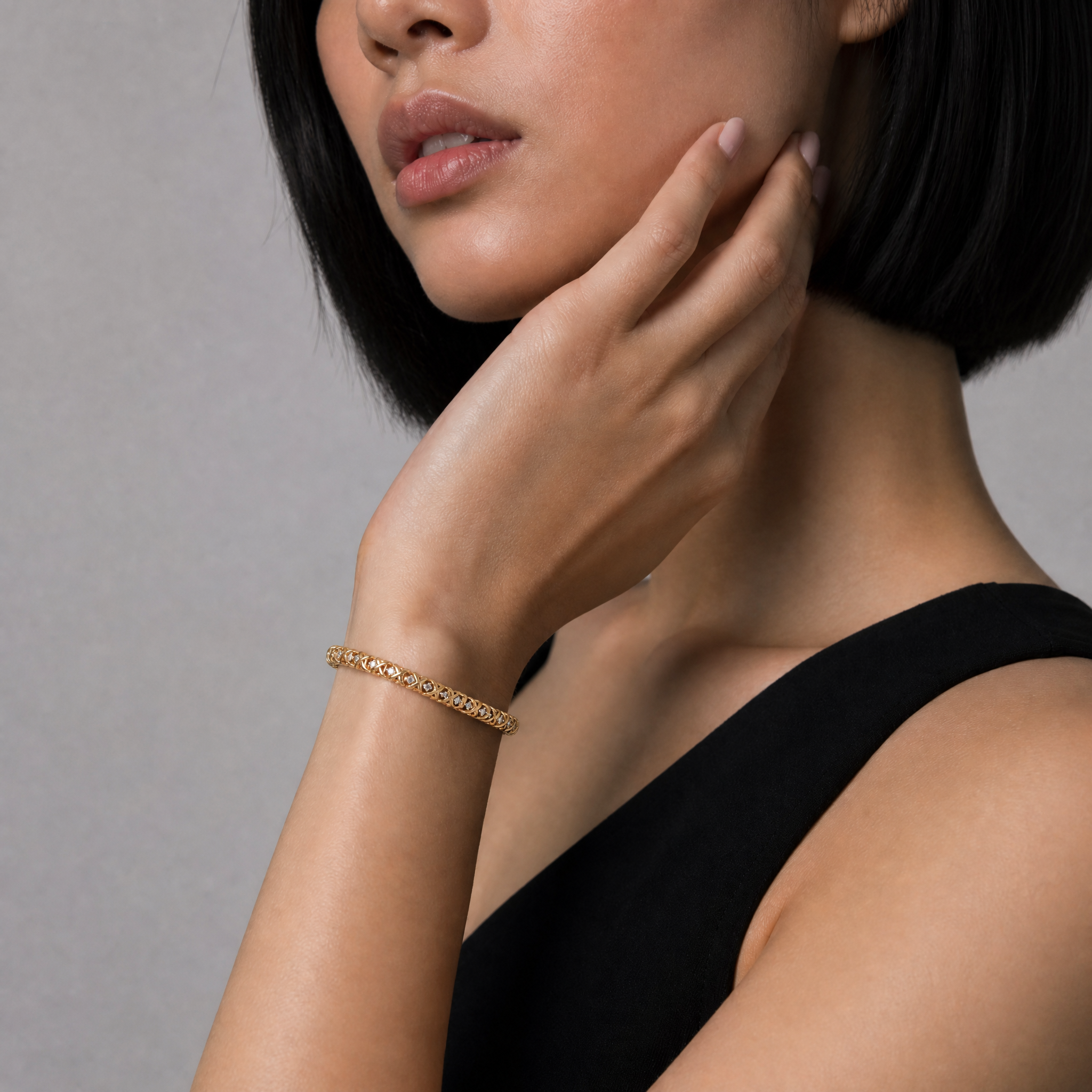 Elegant female model wearing a yellow gold diamond X-link bracelet by Raul Diamonds featuring round lab grown diamonds in an intricate woven luxury bracelet design