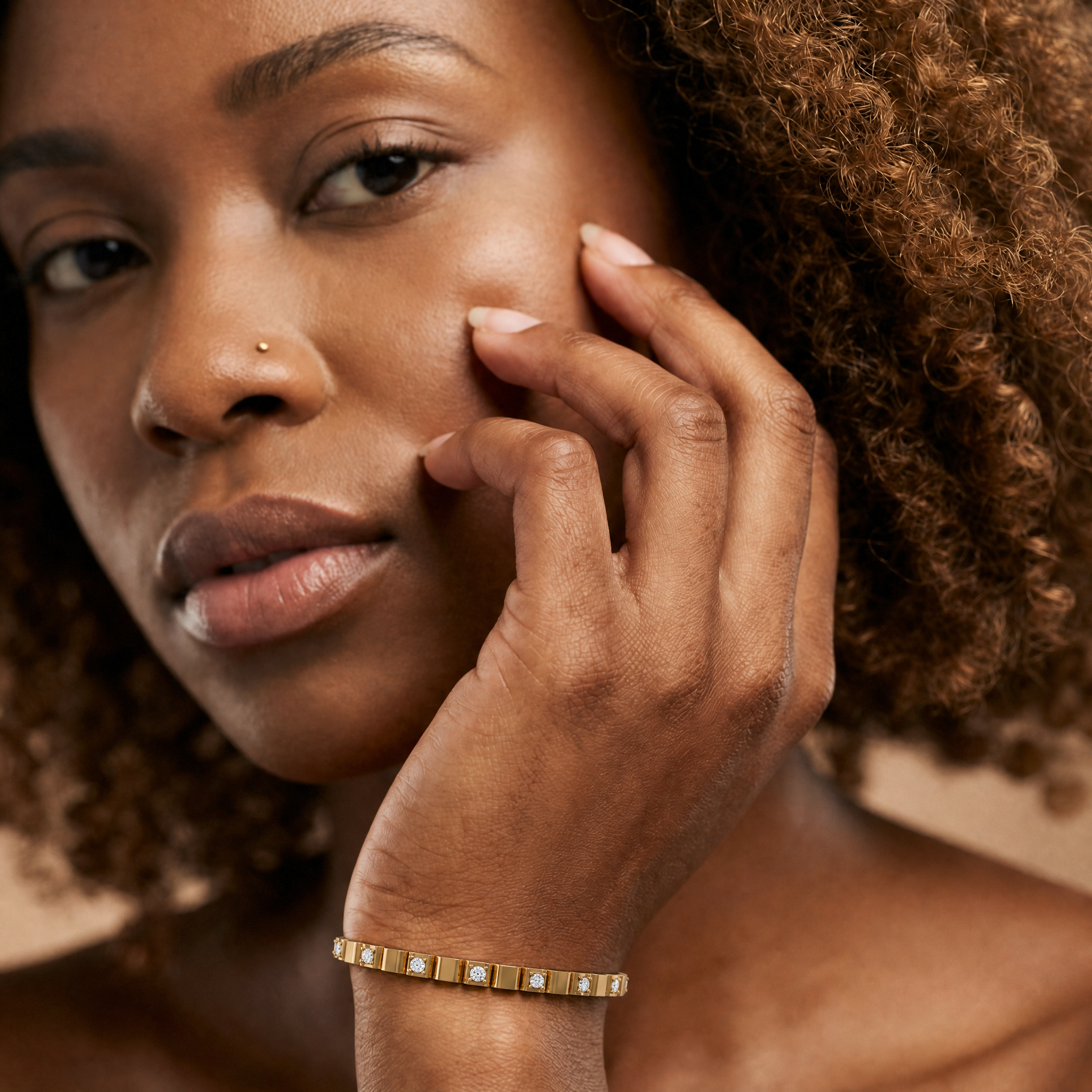 Luxury female model wearing a minimalist yellow gold lab grown diamond tennis bracelet by Raul Diamonds featuring sleek bezel-set round diamonds and modern fine jewelry elegance