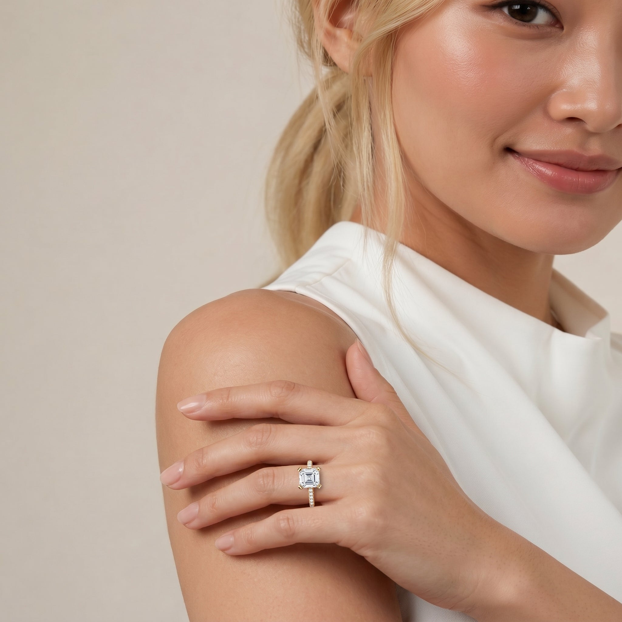 A sophisticated hand-shot of the Aurora Solitaire by Raul Diamonds, featuring a center Asscher cut diamond set on a shimmering micro-pavé band in 14k gold.