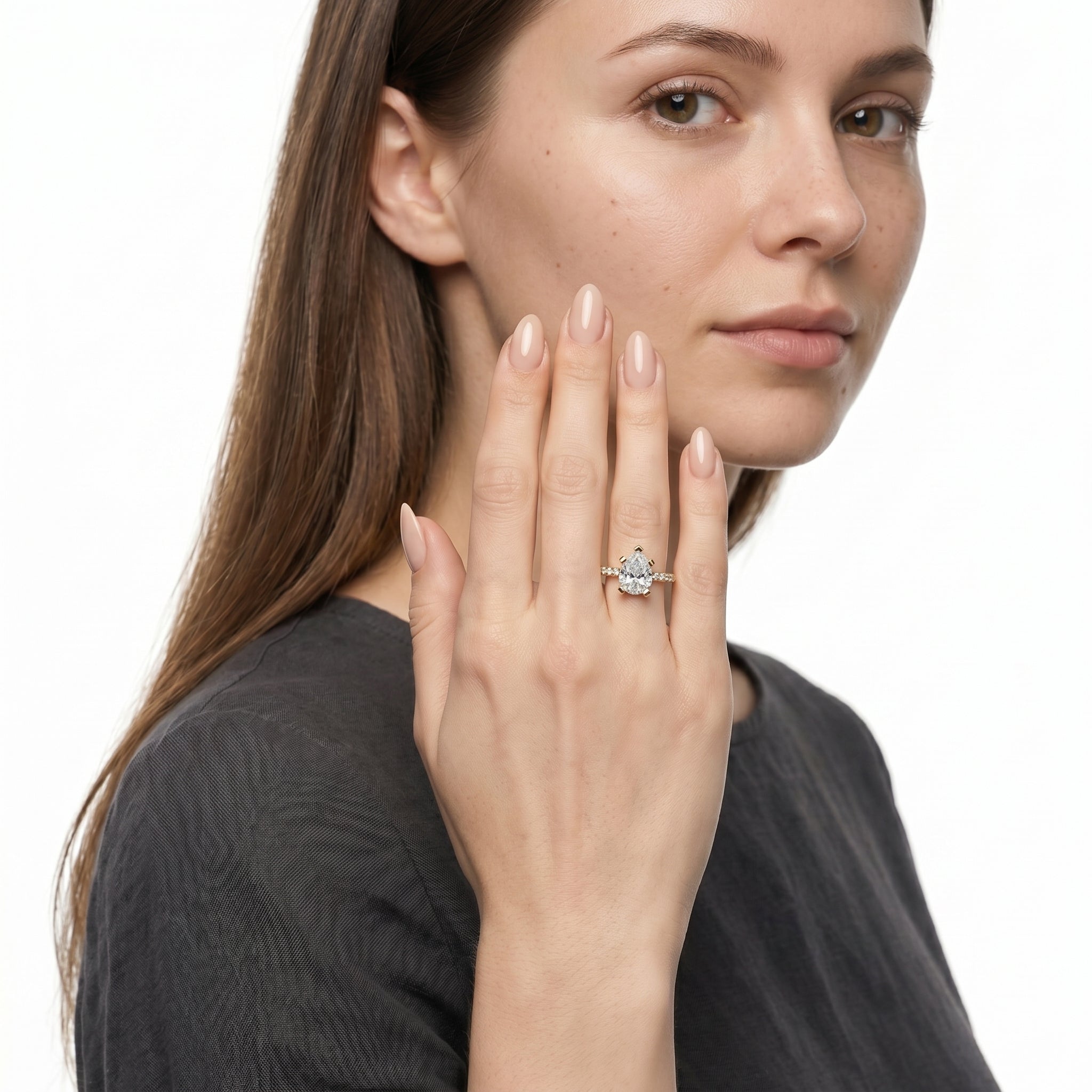 A sophisticated hand-shot of the Lyra Pear Solitaire by Raul Diamonds, featuring a brilliant pear-cut teardrop diamond center stone on a sparkling diamond-set pavé band.