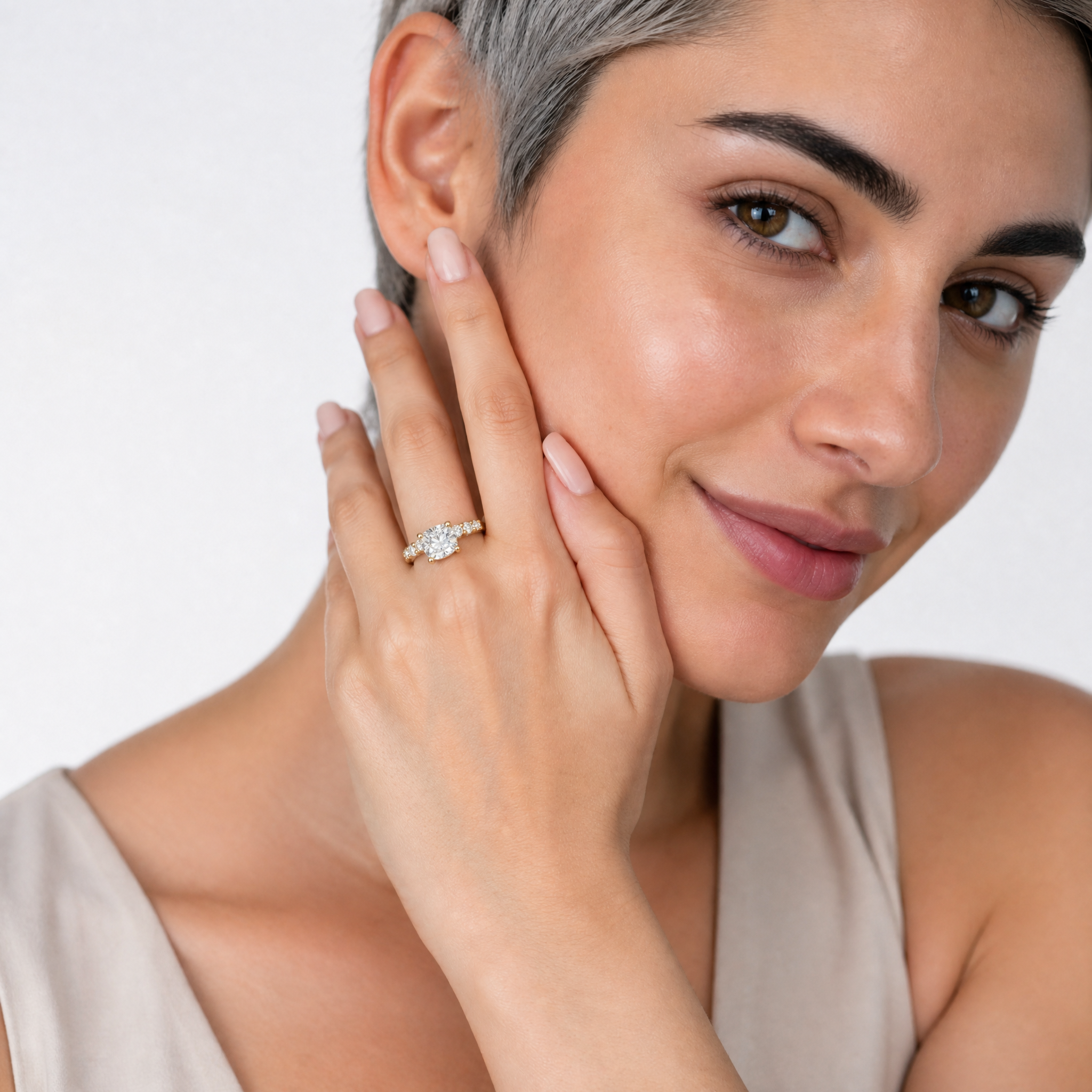 A hand model wearing a Raul Diamonds cushion-cut diamond engagement ring with a hidden halo and eternity band setting