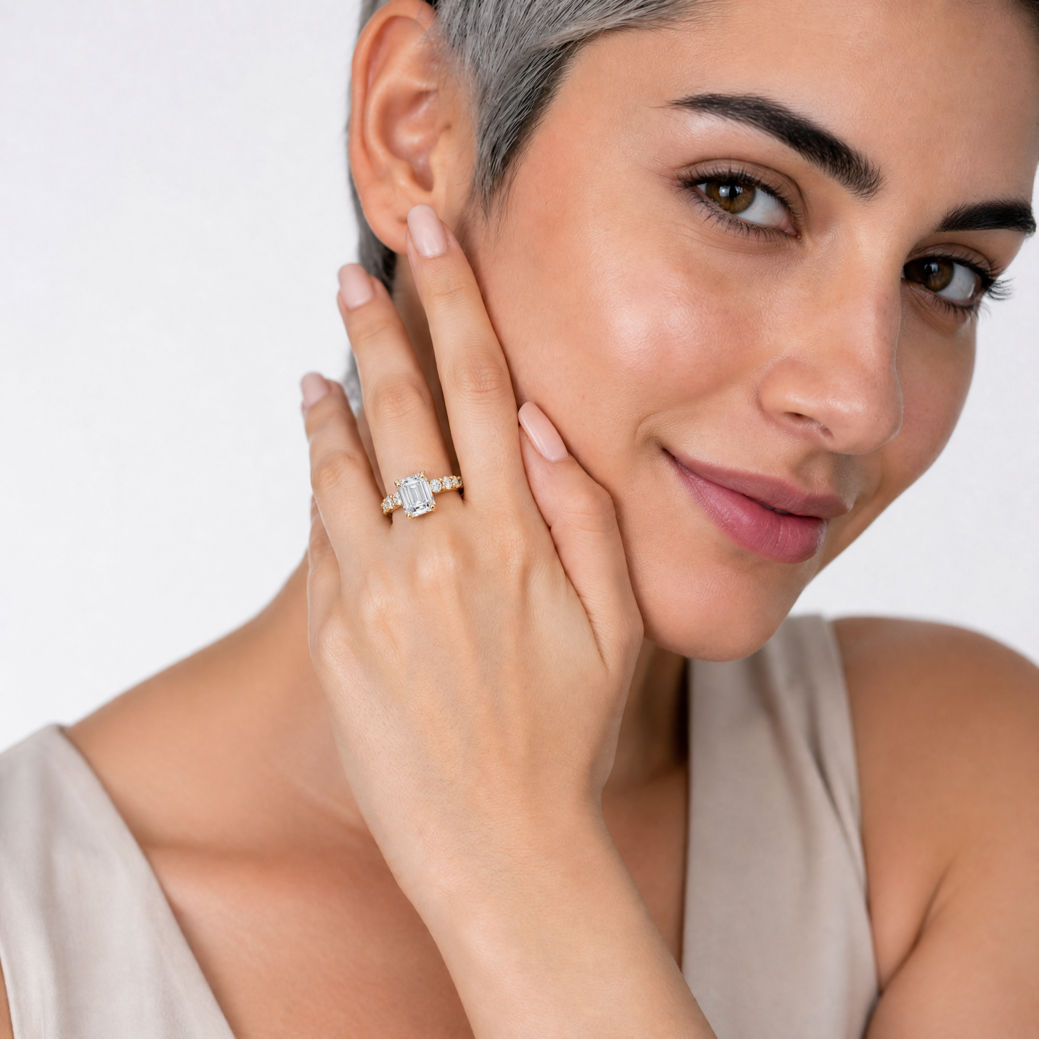 A hand model showcasing a Raul Diamonds emerald-cut diamond engagement ring featuring a hidden halo and a shared-prong eternity diamond band