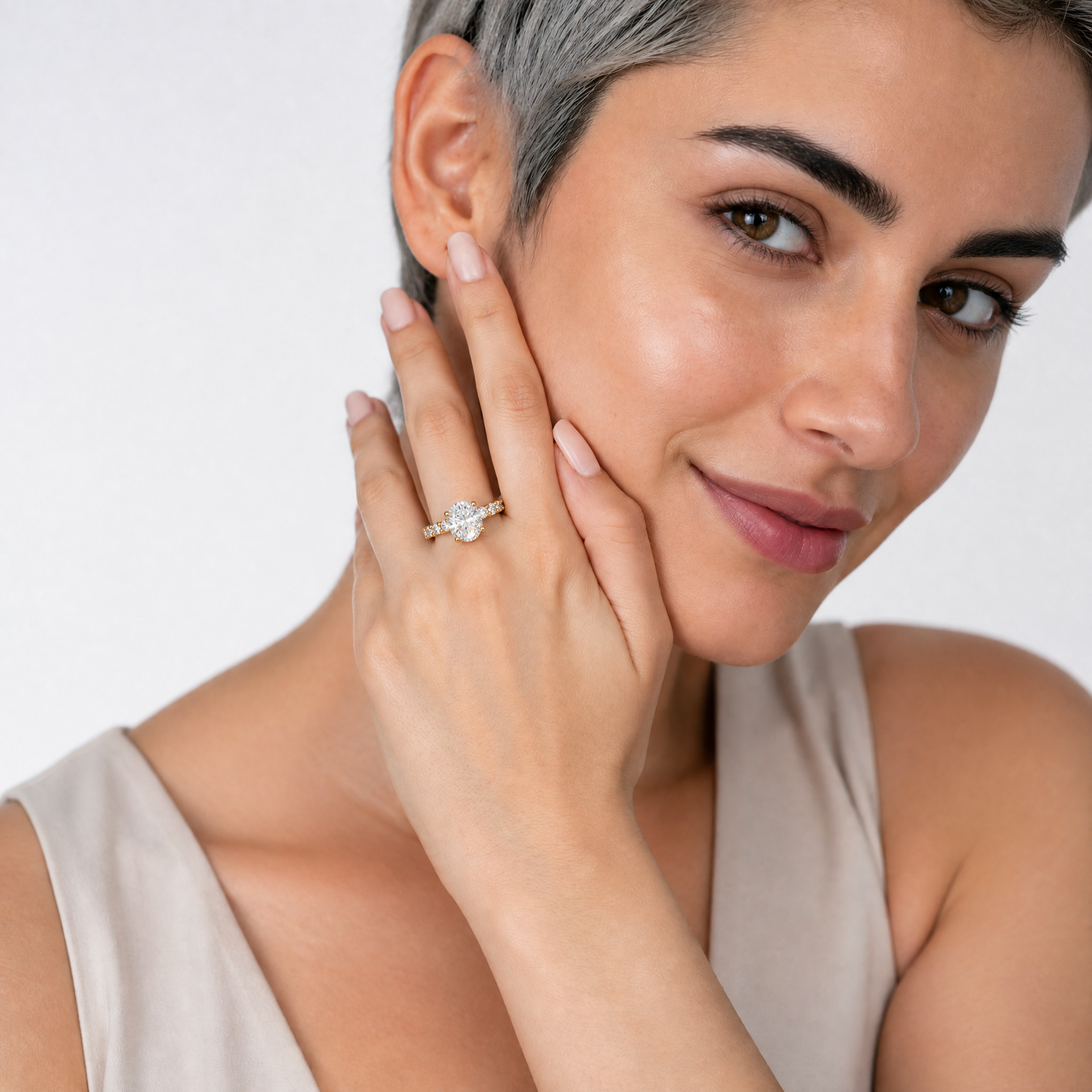 A hand model wearing a Raul Diamonds oval-cut diamond engagement ring, showcasing the elongated center stone and a full-circle eternity diamond band
