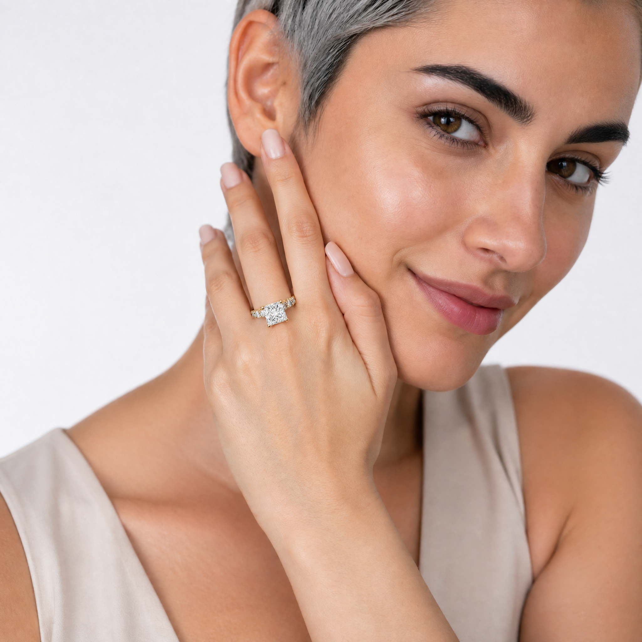 A hand model wearing a Raul Diamonds princess-cut diamond engagement ring featuring a high-polish eternity band and a hidden halo setting