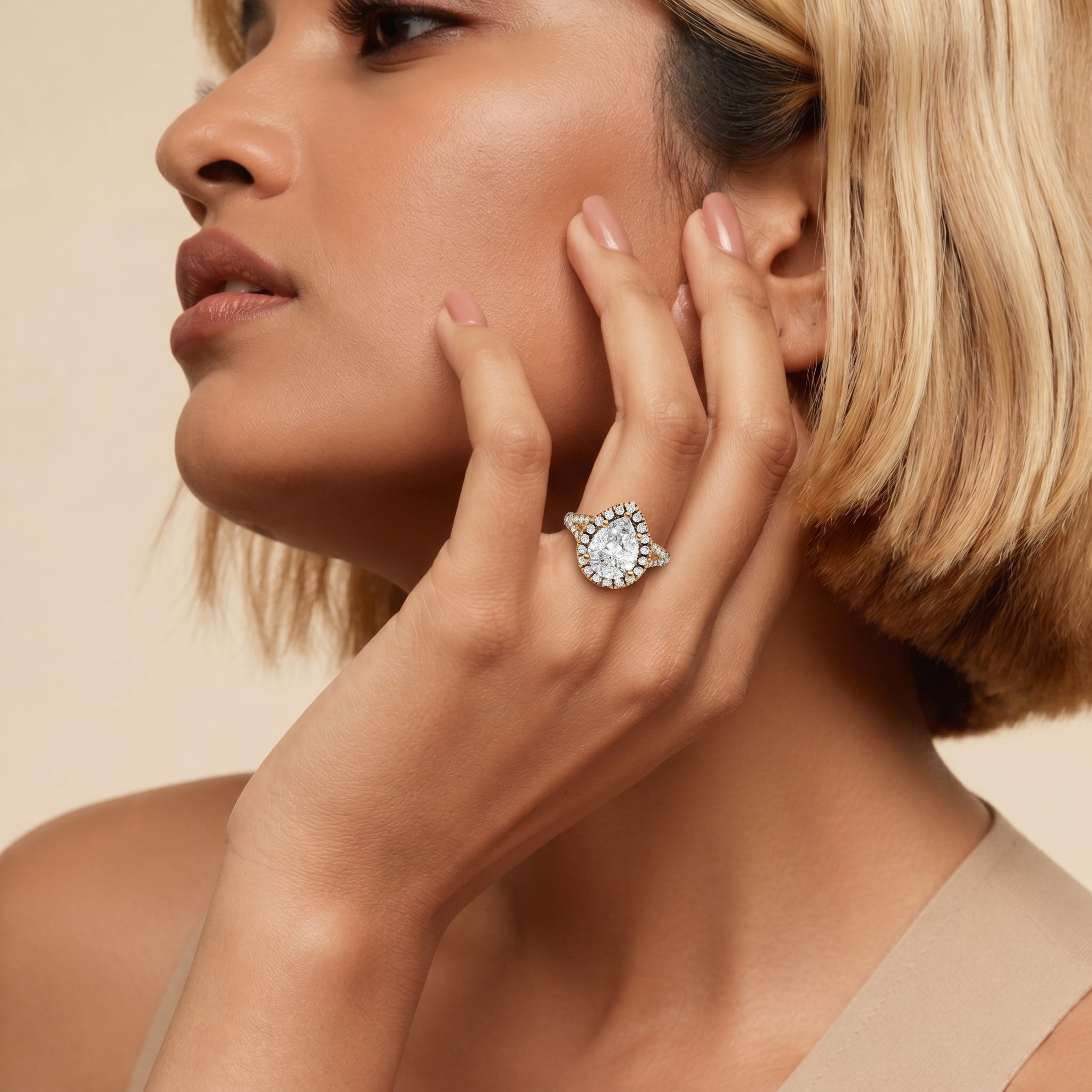 A model's hand featuring a Raul Diamonds pear-cut diamond engagement ring, showcasing the elegant teardrop shape, sparkling pavé halo, and unique split shank band