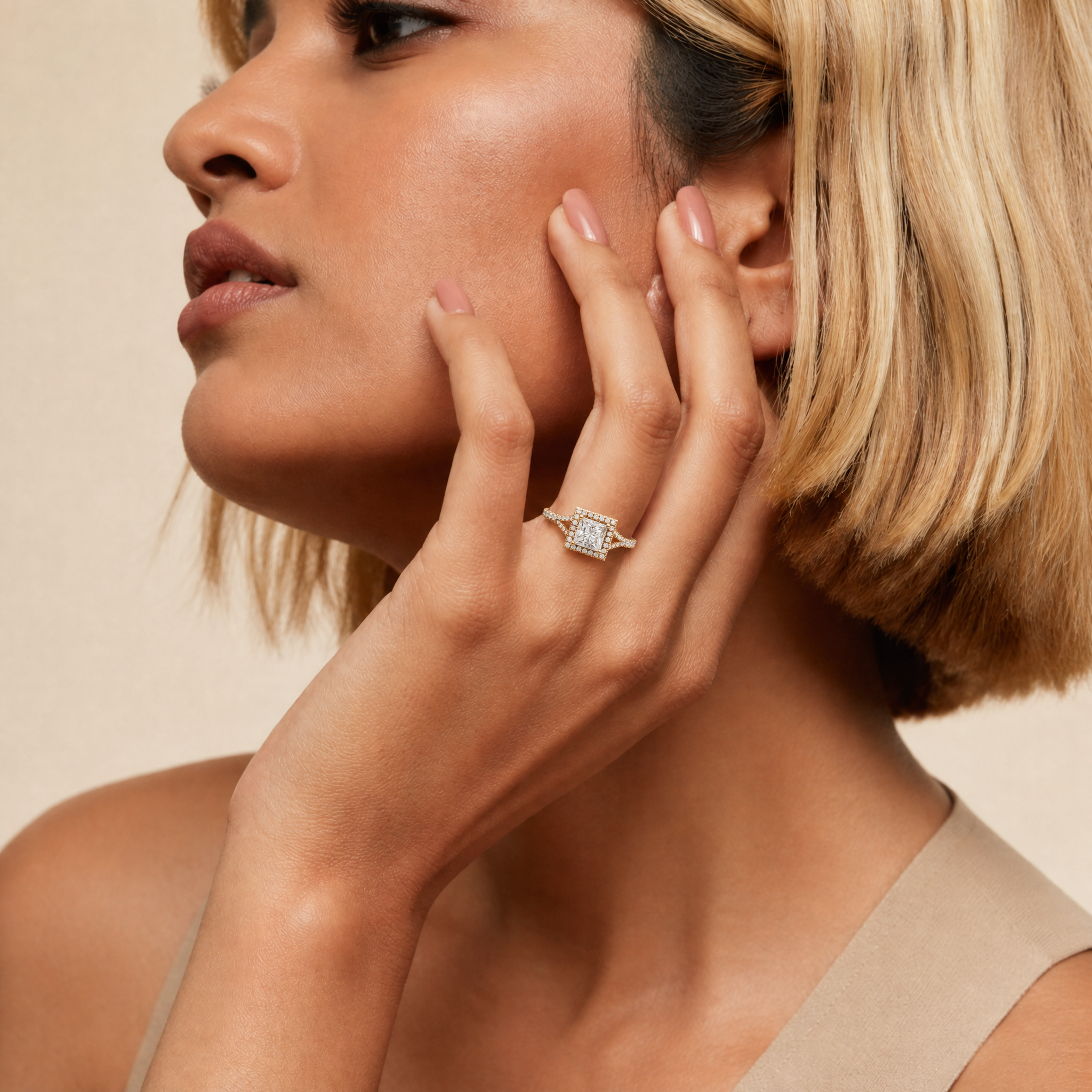 A model's hand wearing a Raul Diamonds princess cut diamond engagement ring, featuring a square-shaped brilliant halo and a diamond-encrusted split shank band