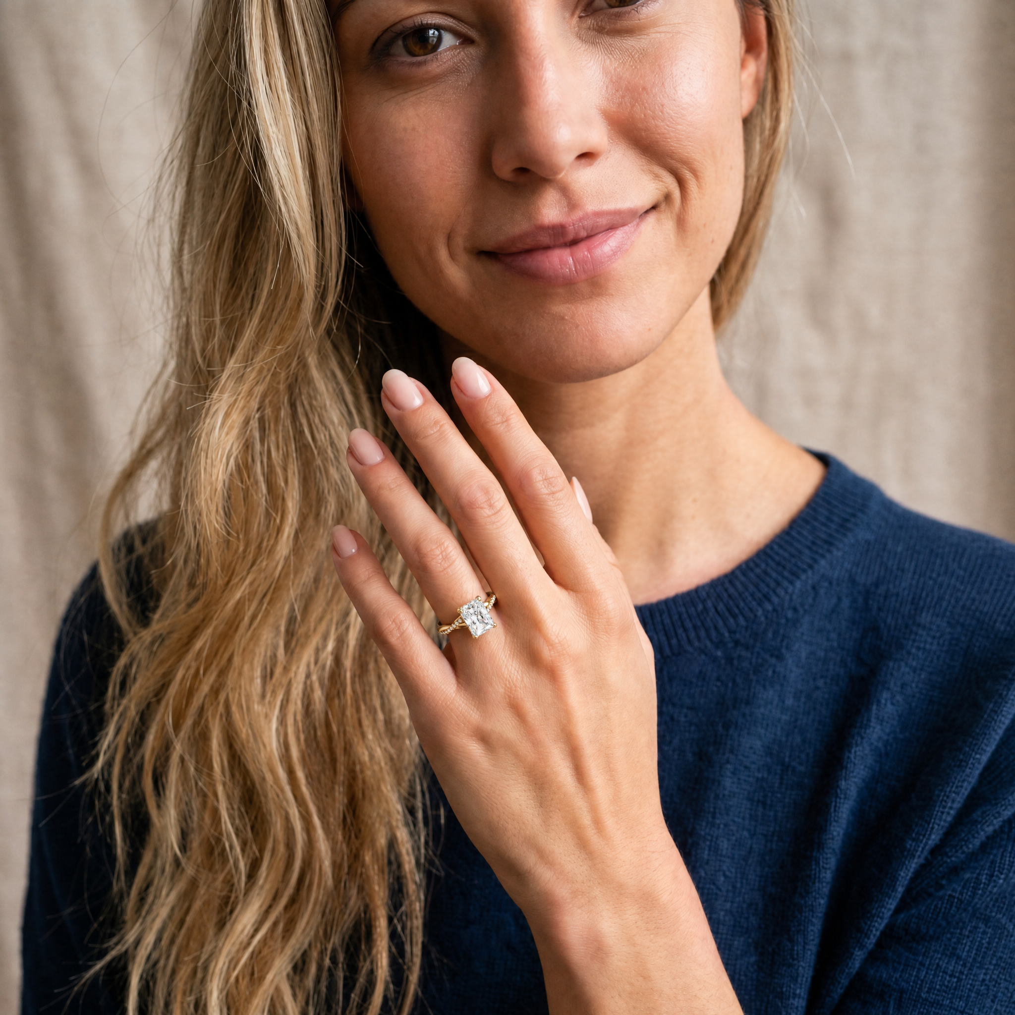 A lifestyle perspective of a model wearing a Raul Diamonds radiant cut diamond ring, showcasing the rectangular brilliant-cut center stone and the elegant pavé twist band on a finger