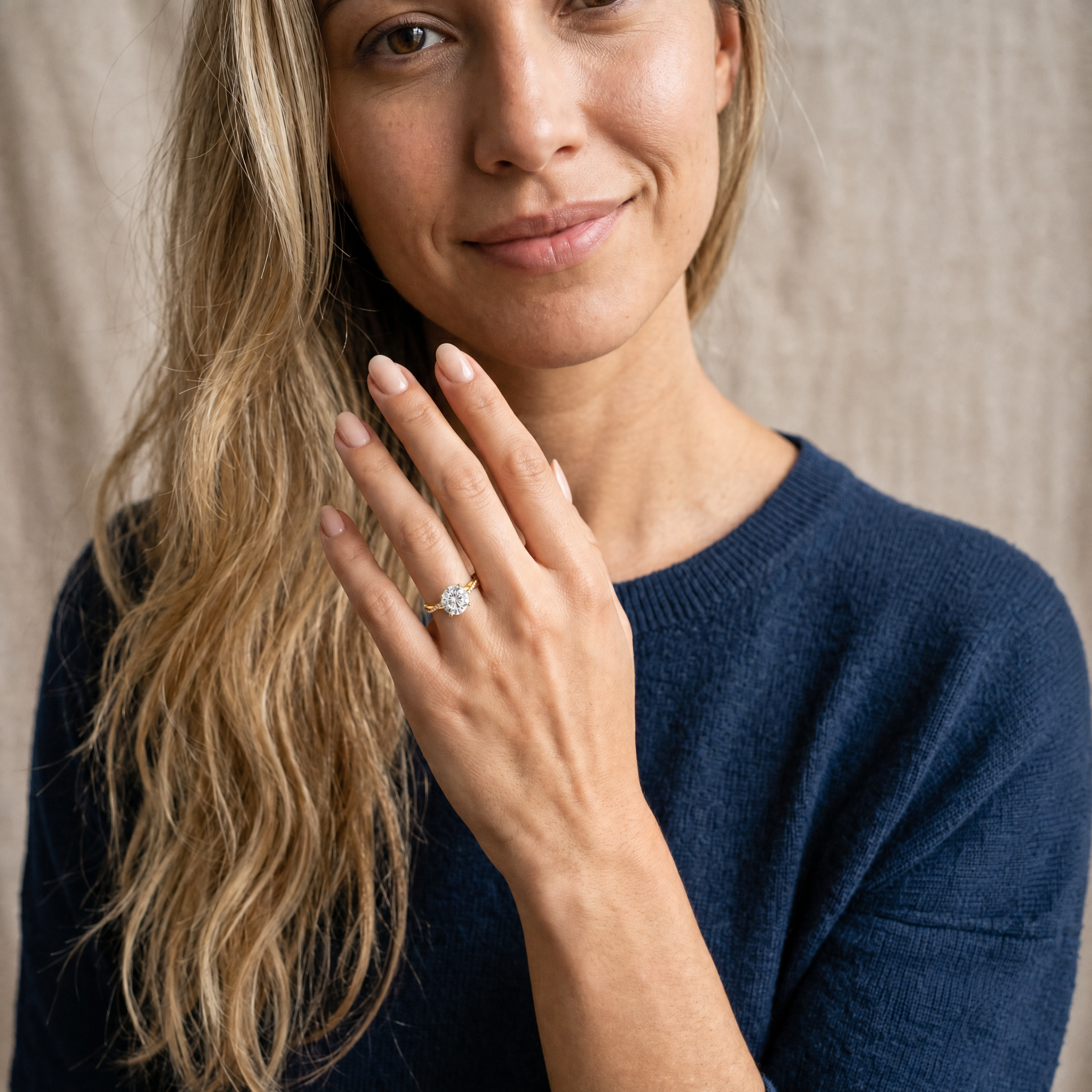 A high-end lifestyle image of a model wearing a Raul Diamonds round brilliant cut engagement ring, showcasing the classic circular diamond and the shimmering twisted pavé band