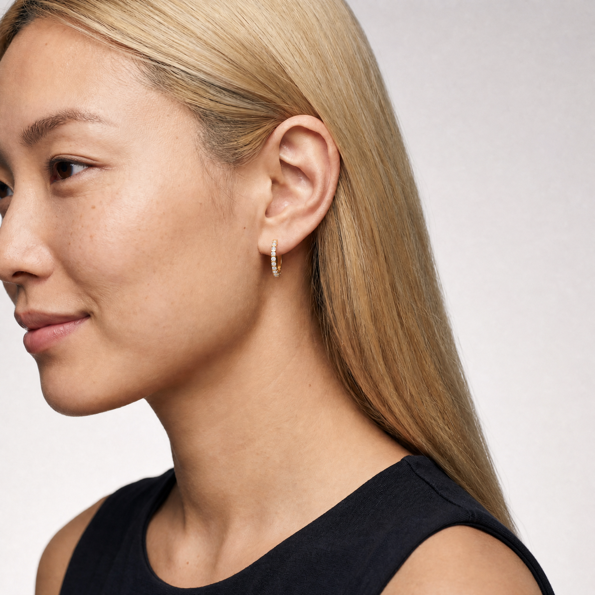 Elegant model wearing Raul Diamonds bezel set diamond hoop earrings with modern luxury styling