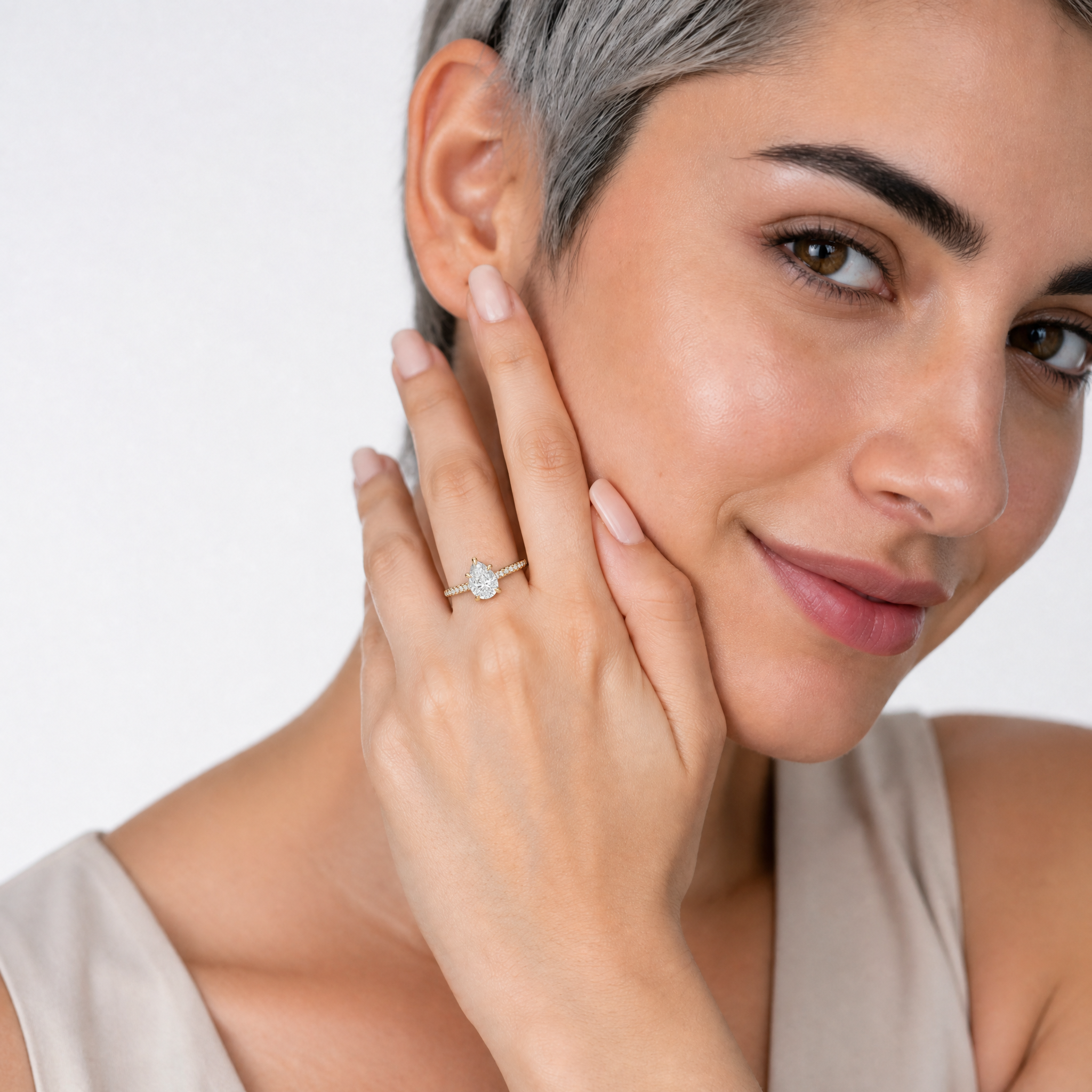 Female model wearing Raul Diamonds pear cut engagement ring in yellow gold with pavé diamond band