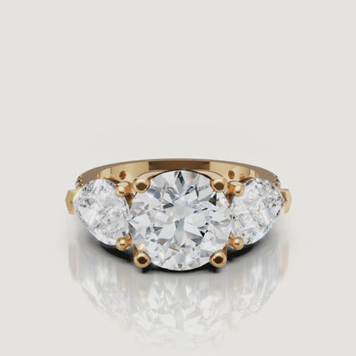 Round cut three stone lab grown diamond engagement ring video featuring elegant model hand movements, pear side stones sparkle, yellow gold band shine, and luxury bridal style by Raul Diamonds