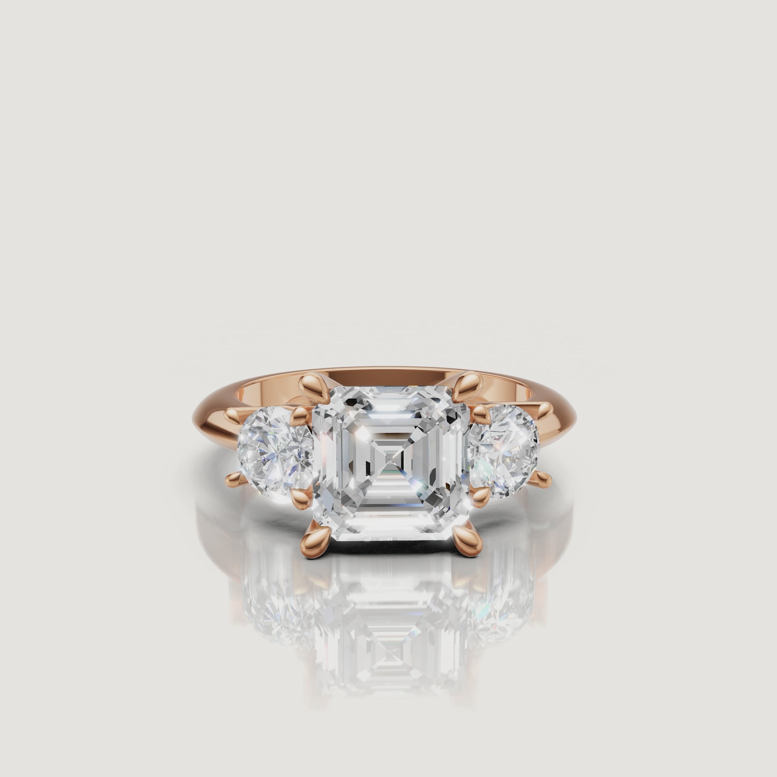 Cinematic close-up of the Athena rose gold Asscher trilogy ring, focusing on the warm blush metal and the high-clarity step-cut facets of the center diamond.