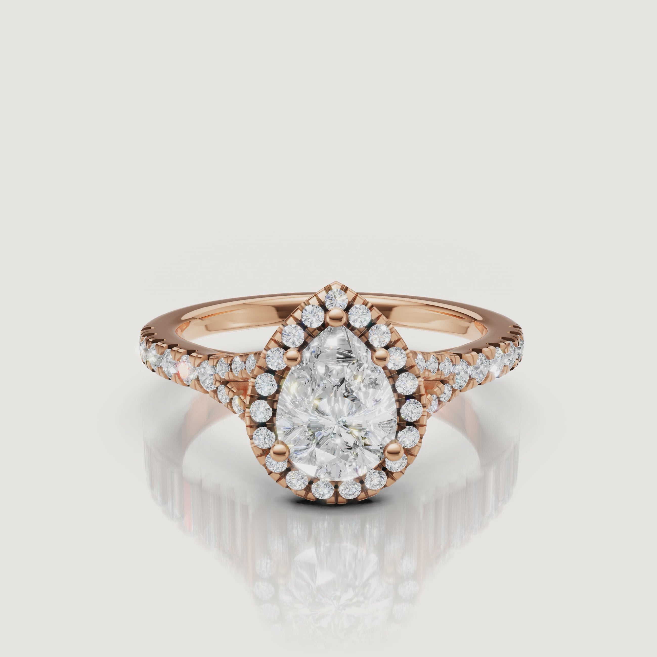 Close-up cinematic video of a rose gold pear-shaped diamond halo ring, showcasing the romantic blush metal and the shimmering diamond-set band
