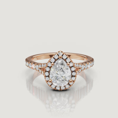 Close-up cinematic video of a rose gold pear-shaped diamond halo ring, showcasing the romantic blush metal and the shimmering diamond-set band