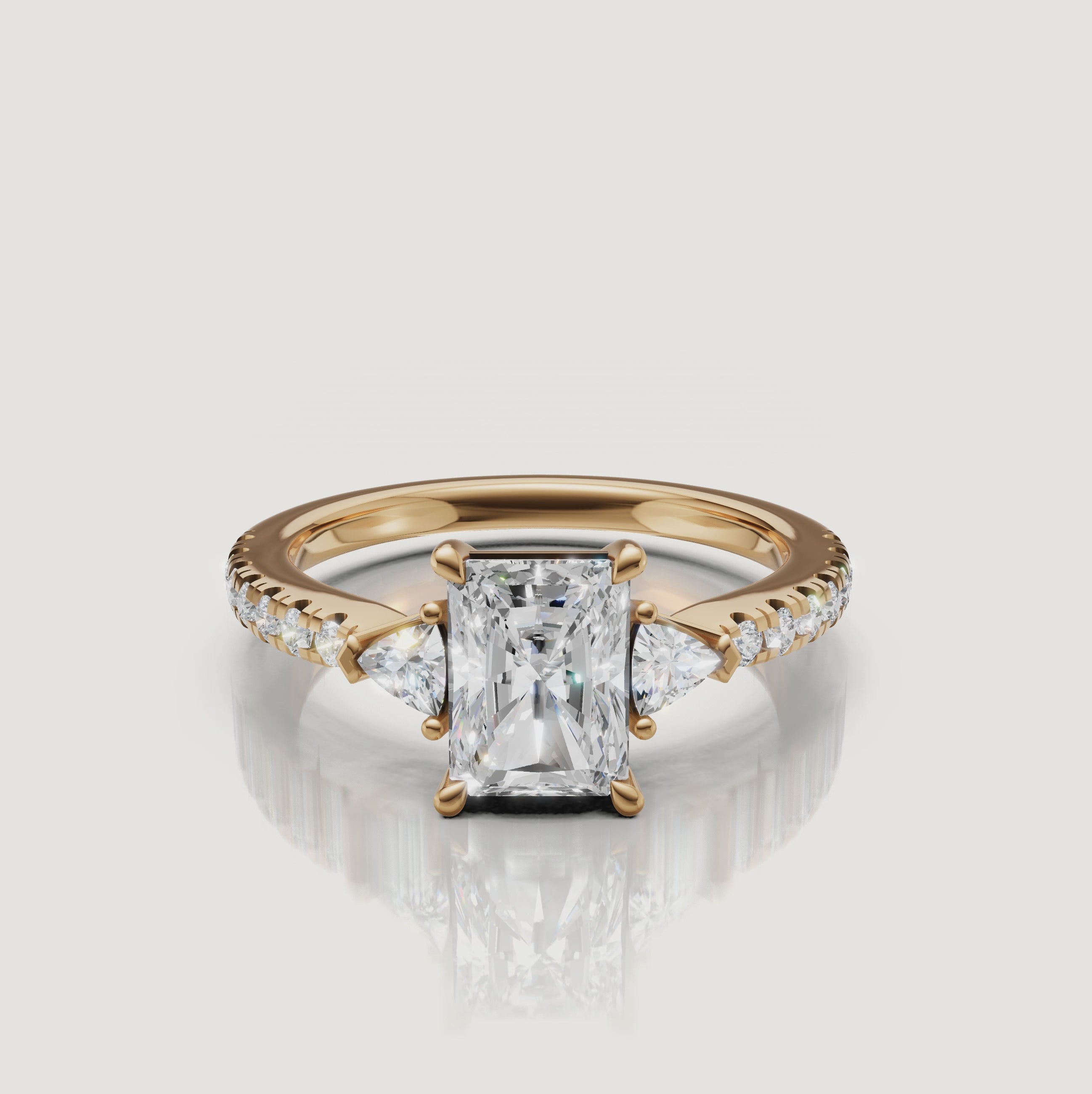 A 360-degree rotation of a Rual Diamonds radiant-cut three-stone ring in 14k yellow gold, showcasing the brilliant trillion side stones and shimmering pavé shank
