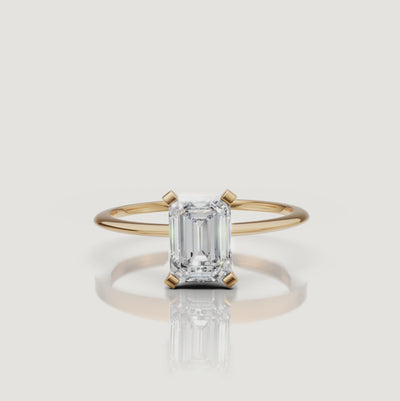 Cinematic video of an emerald cut lab grown diamond solitaire engagement ring in yellow gold by Raul Diamonds featuring elegant hand movement, macro diamond sparkle, warm luxury lighting, and premium bridal jewelry styling