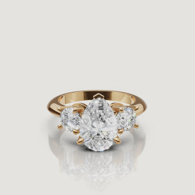 360-degree video showcase of the Raul Diamonds pear cut three-stone ring in yellow gold, highlighting the elegant teardrop shape and the fire of the round side diamonds.