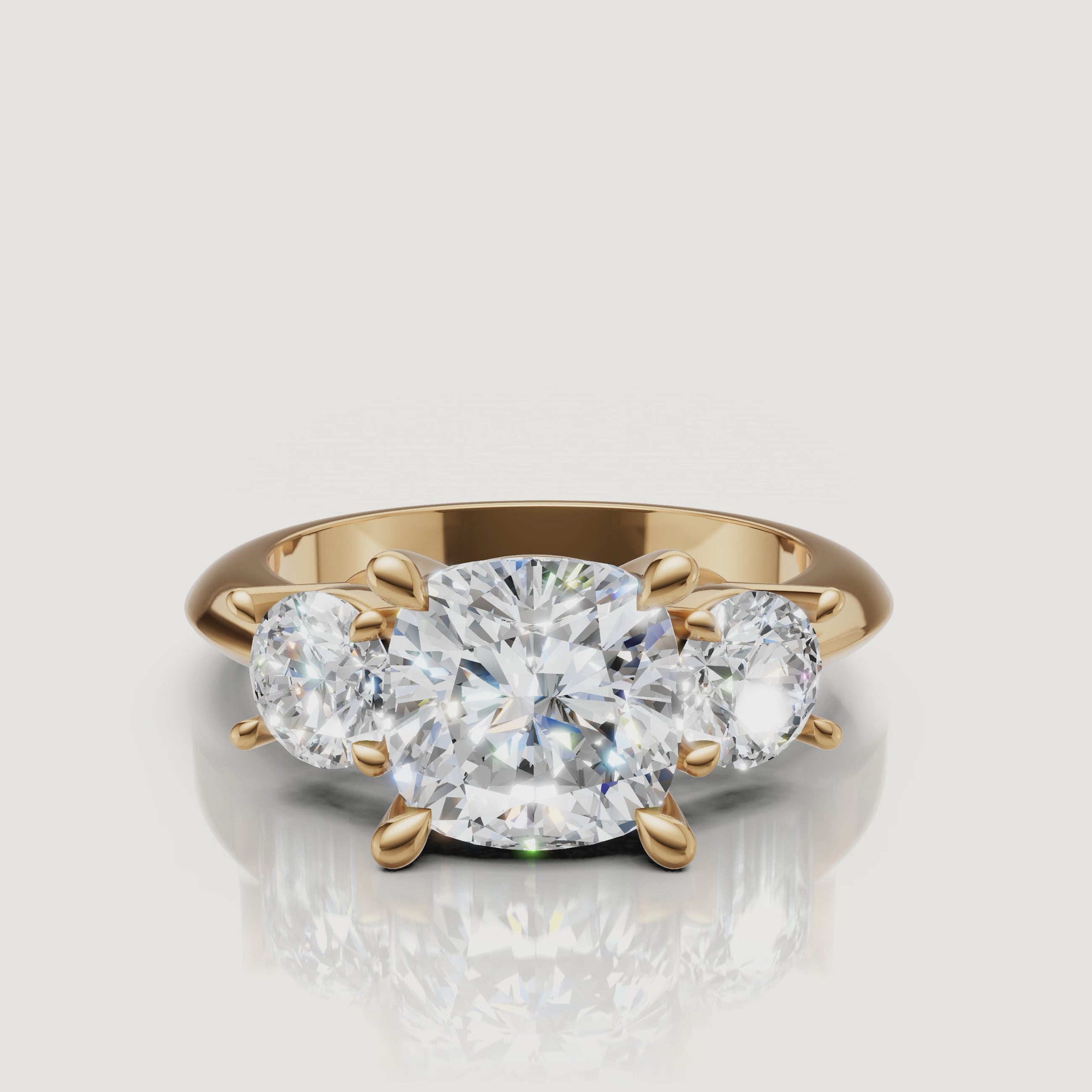360-degree video showcase of the Raul Diamonds cushion cut three-stone ring in yellow gold, highlighting the soft pillow shape and the fire of the round side diamonds.
